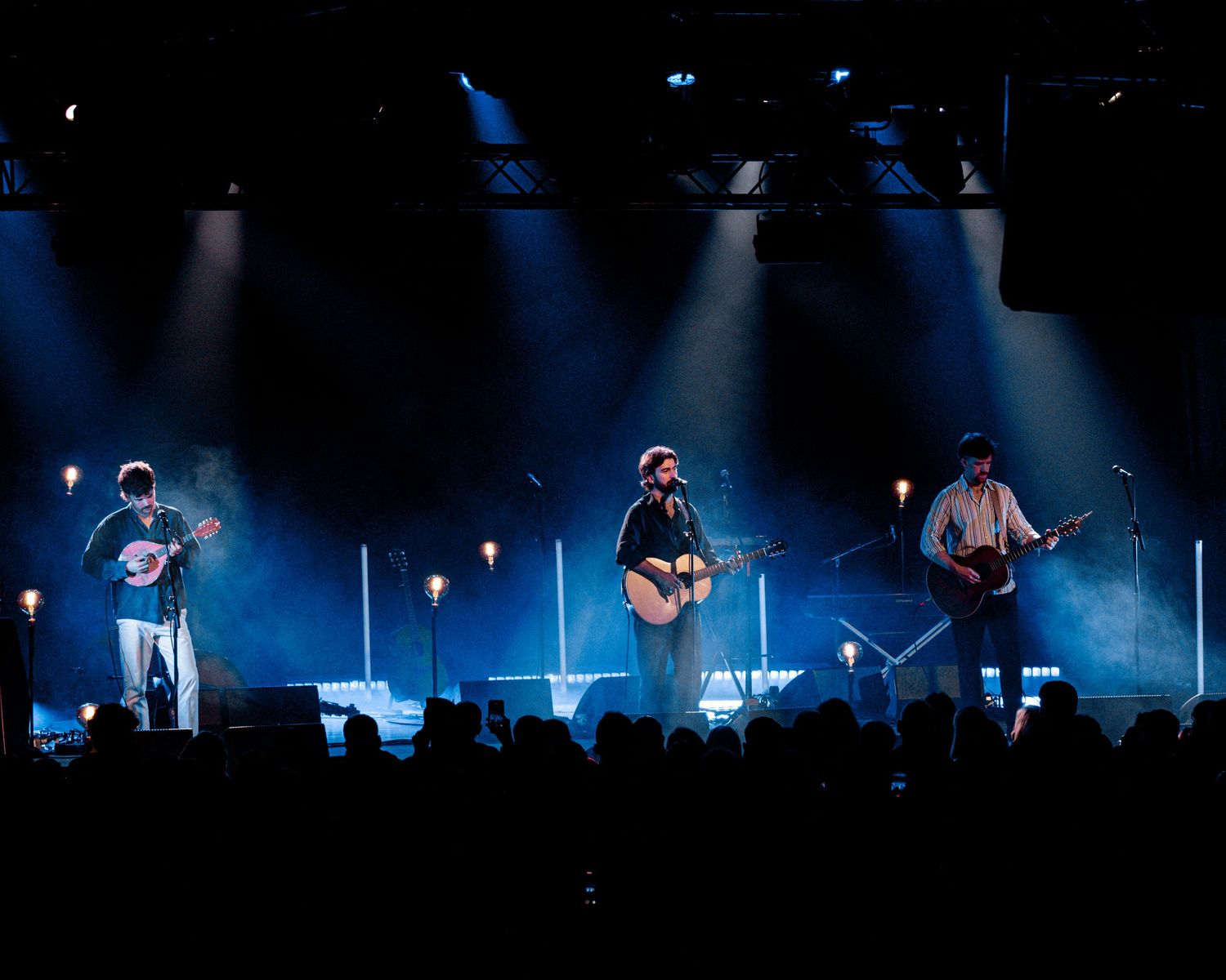 Concert stage illuminated with dramatic blue lighting and silhouetted performers creating an atmospheric scene.