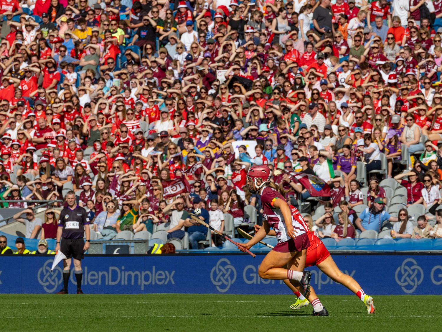 Large crowd of enthusiastic fans in red jerseys filling stadium seats during a match.