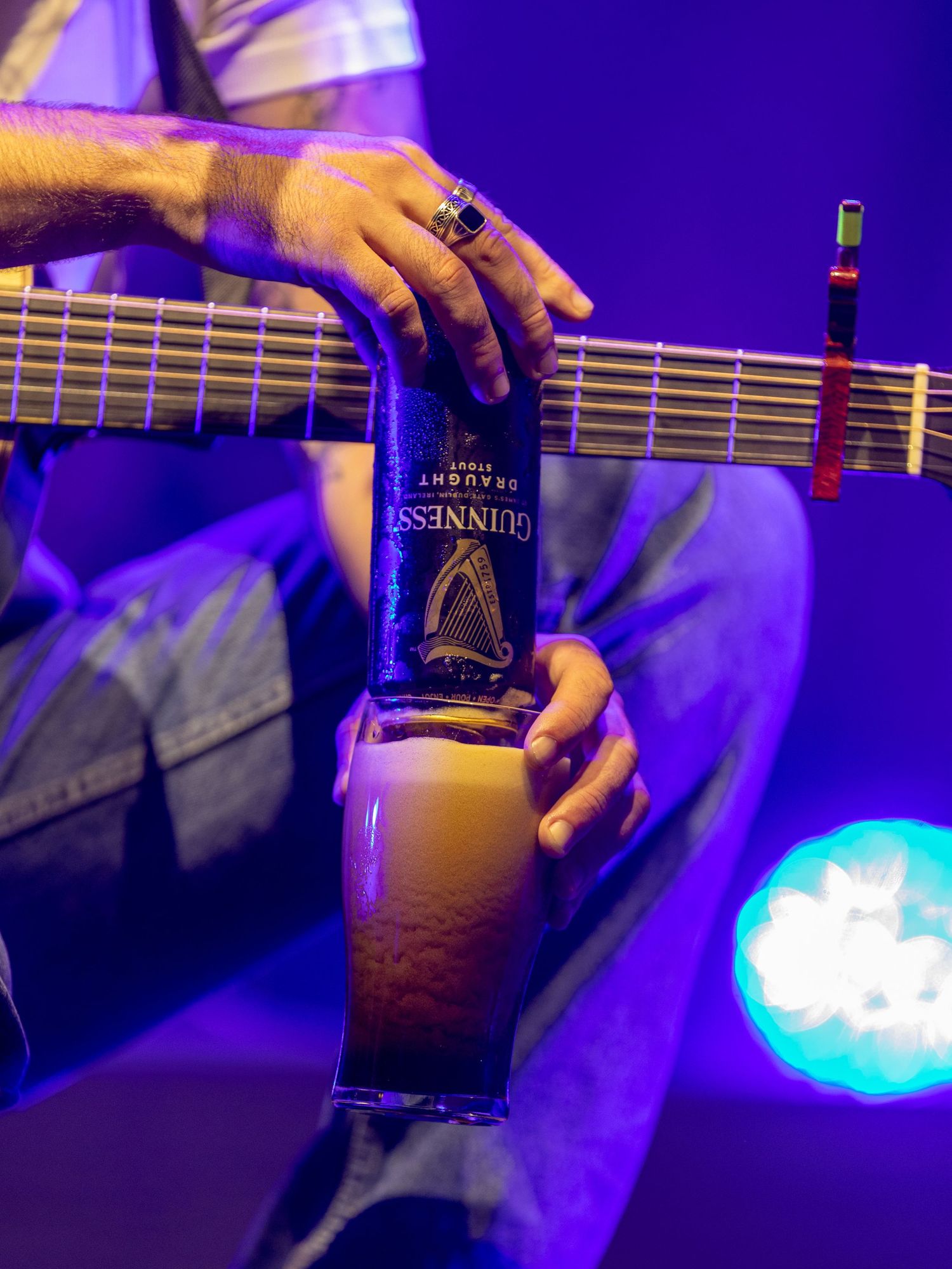 Close-up shots of hands playing bass guitar under dramatic purple stage lighting.