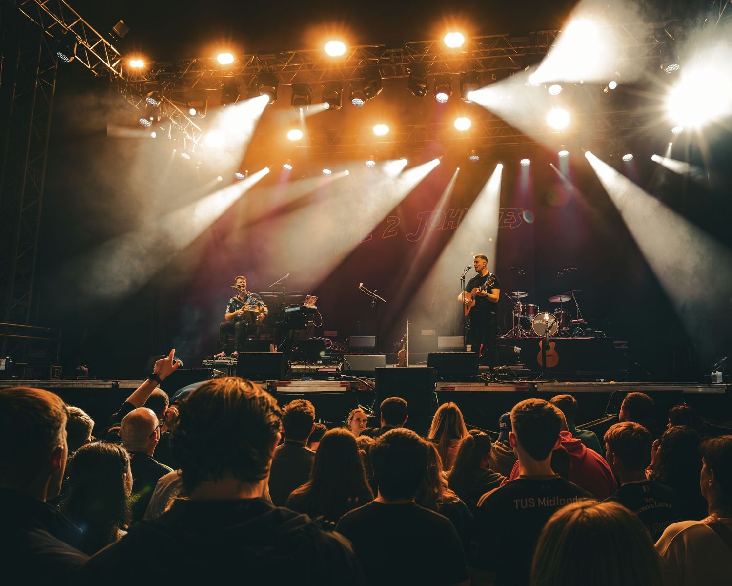Concert crowd silhouettes against bright stage lights during a live music performance at a rock show.