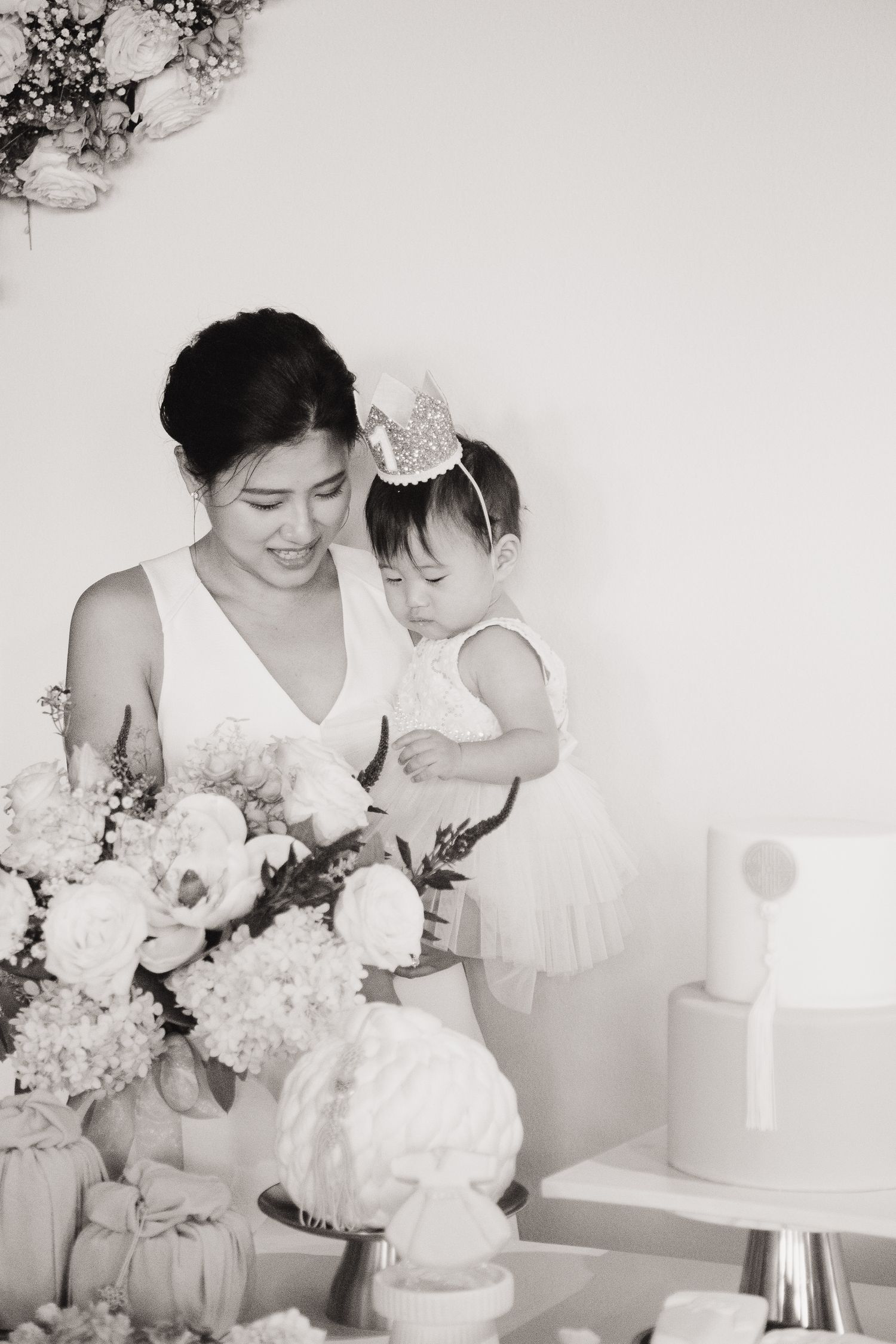 Black and white photograph of a mother holding her daughter during her first birthday party. Korean birthday celebration.