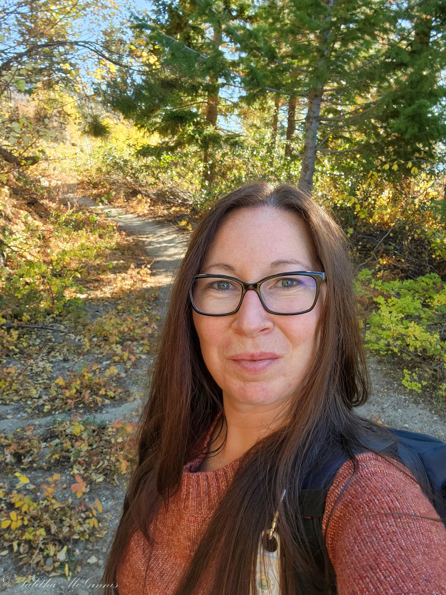 Autumn selfie series showing someone in a brown sweater and glasses against a backdrop of golden fall foliage.
