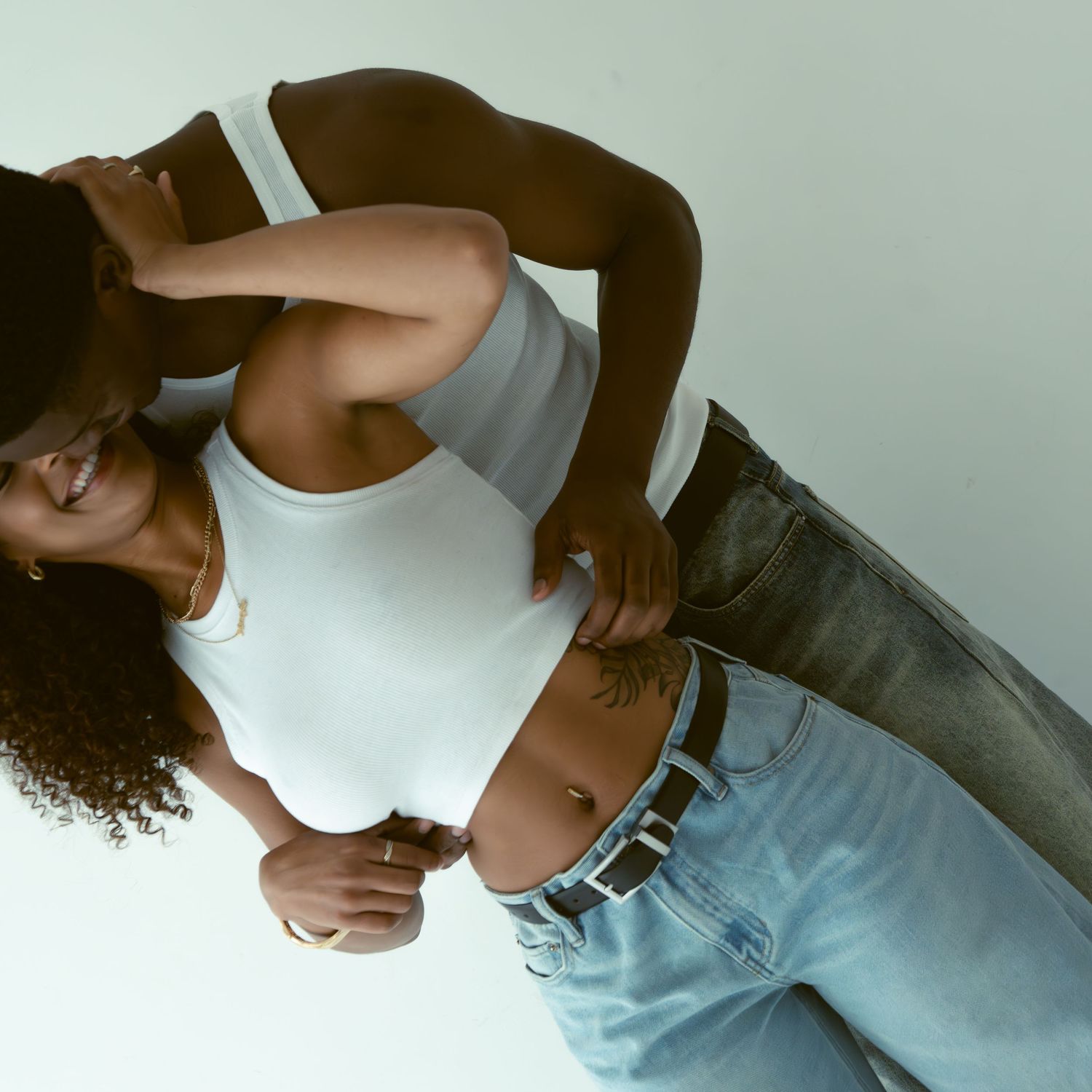 Stylish woman in white crop top and light blue jeans posing against a clean white background.