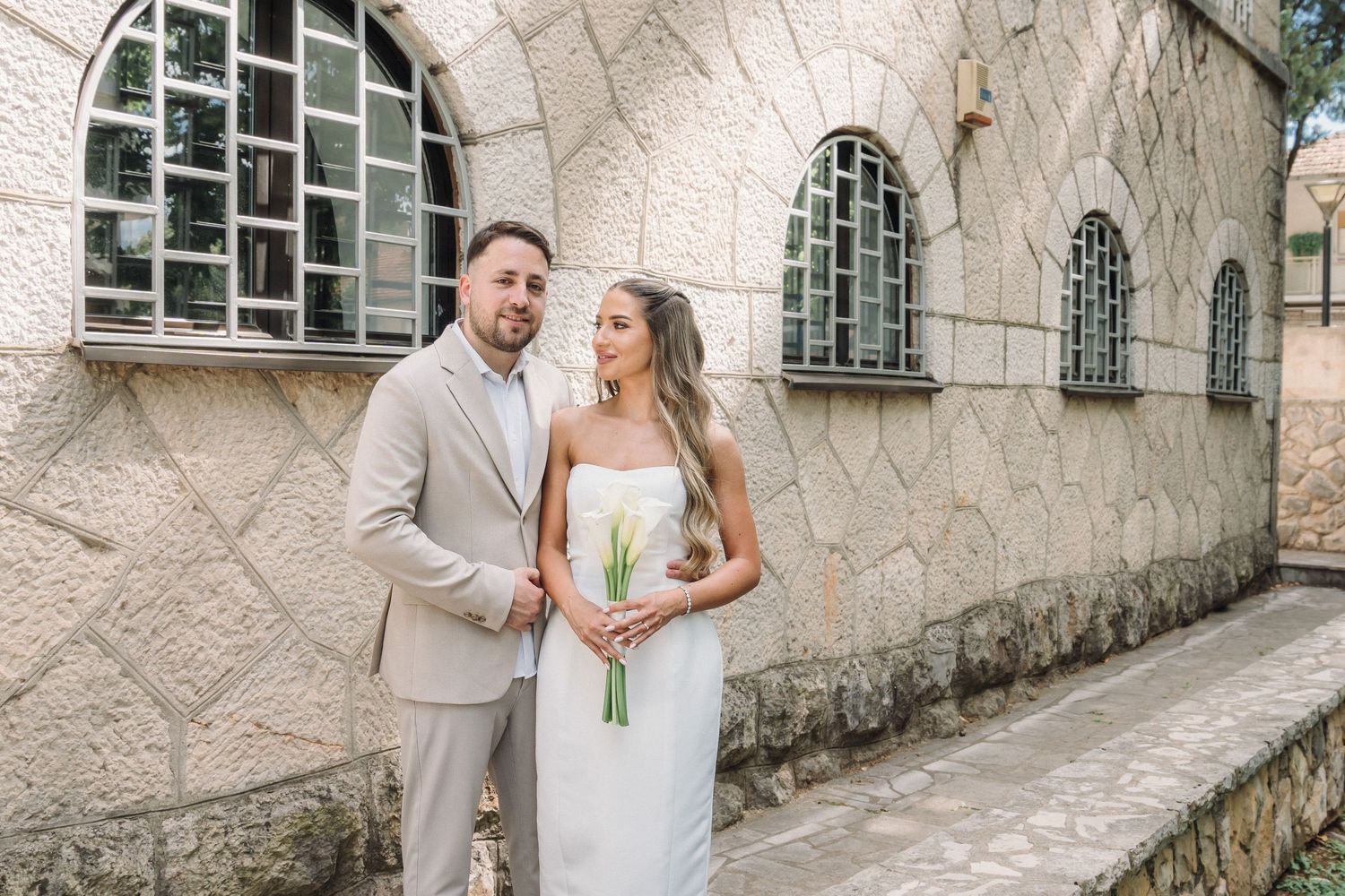 Mladenci pozitraju ispred kamene zgrade, vjenčanje Hercegovina