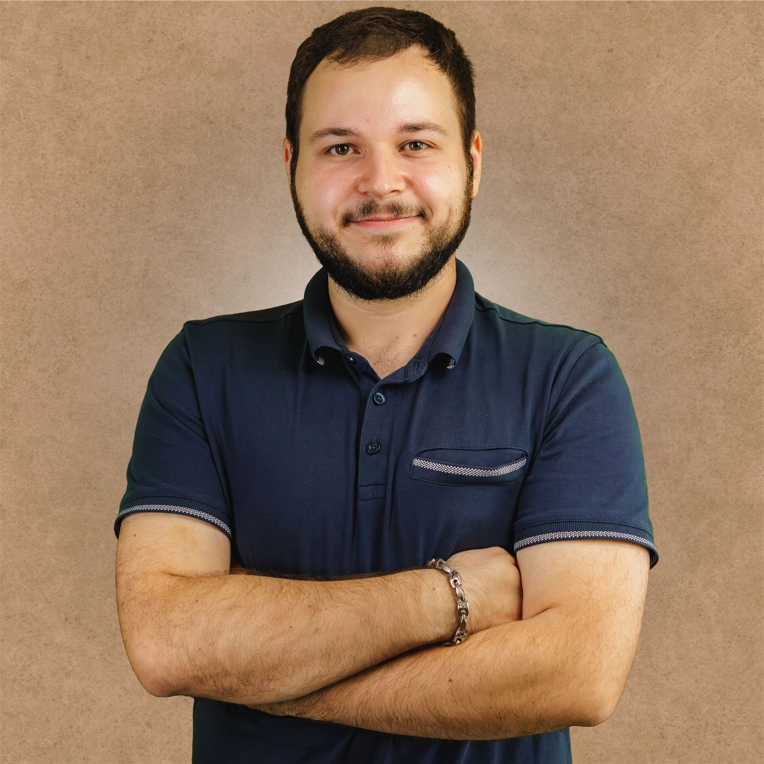Professional headshot of a person wearing a navy polo shirt against a neutral beige background.