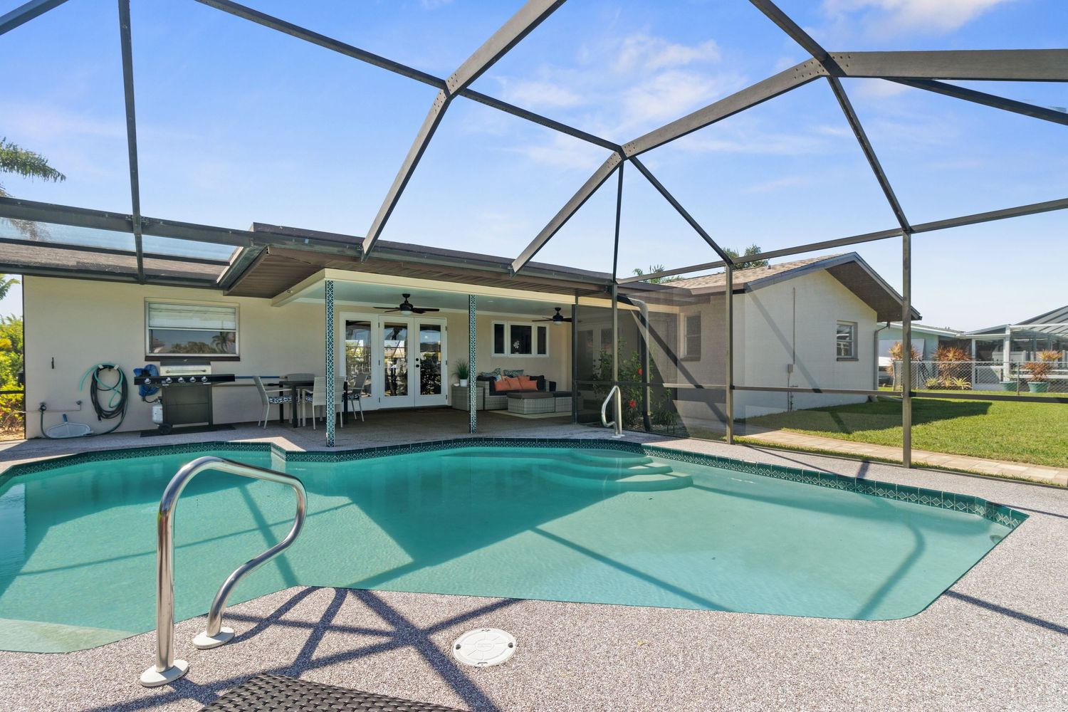 Covered swimming pool with screened enclosure and patio furniture visible through multiple angles of the same space.