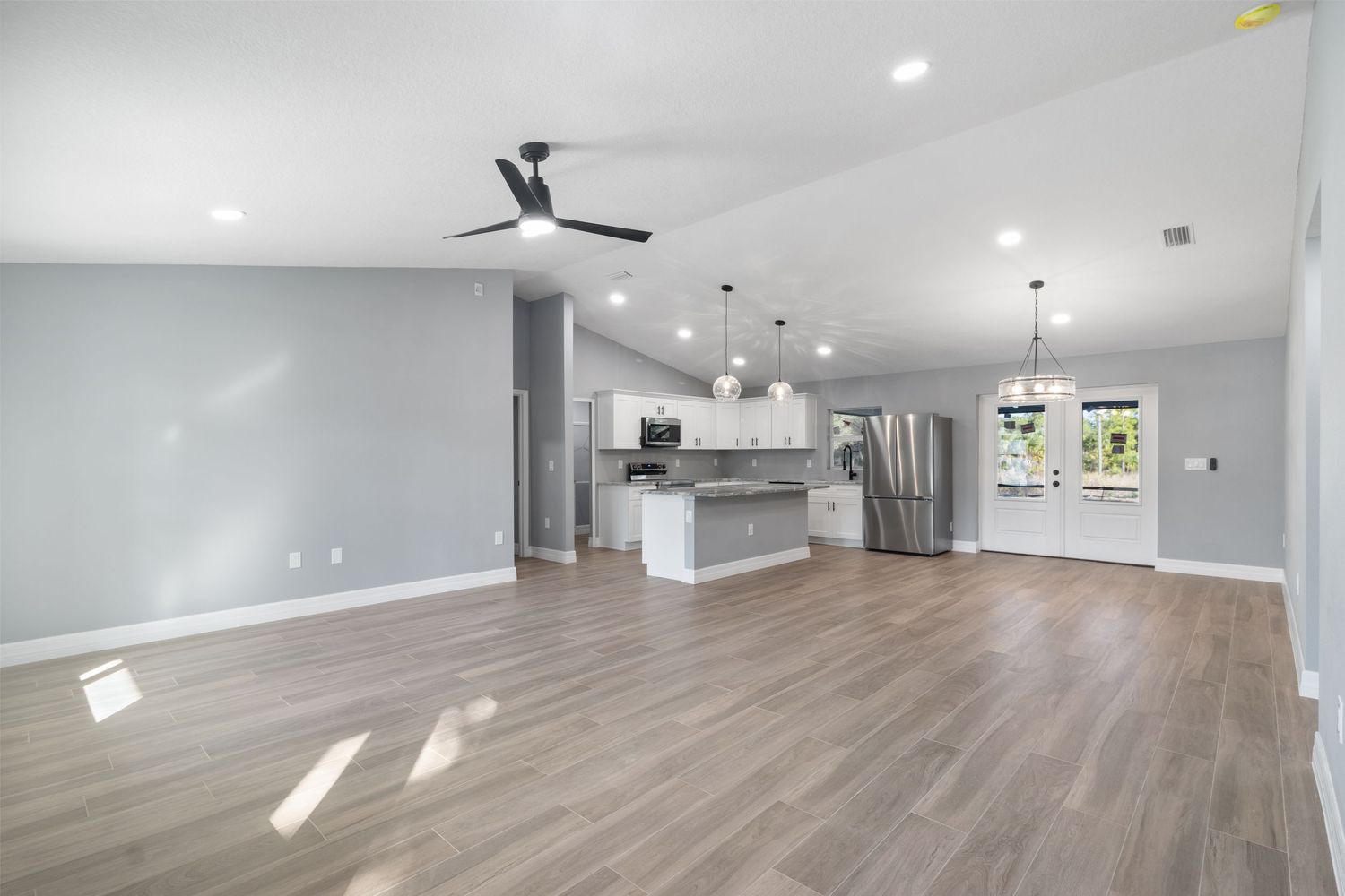 Spacious open-concept living area with hardwood floors, modern kitchen, and ceiling fan.