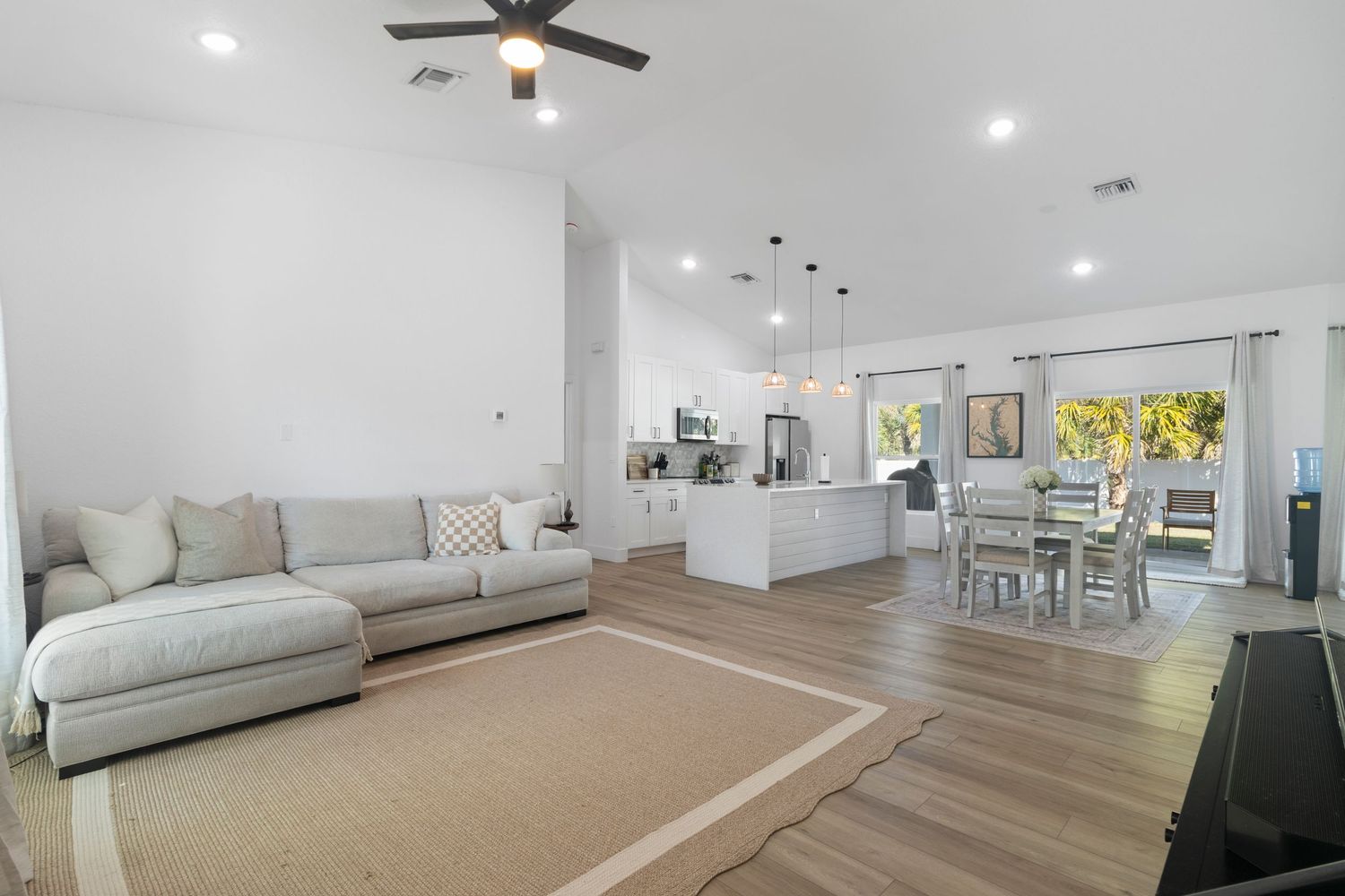A bright and spacious open-concept living room with a couch, dining table, and kitchen visible.