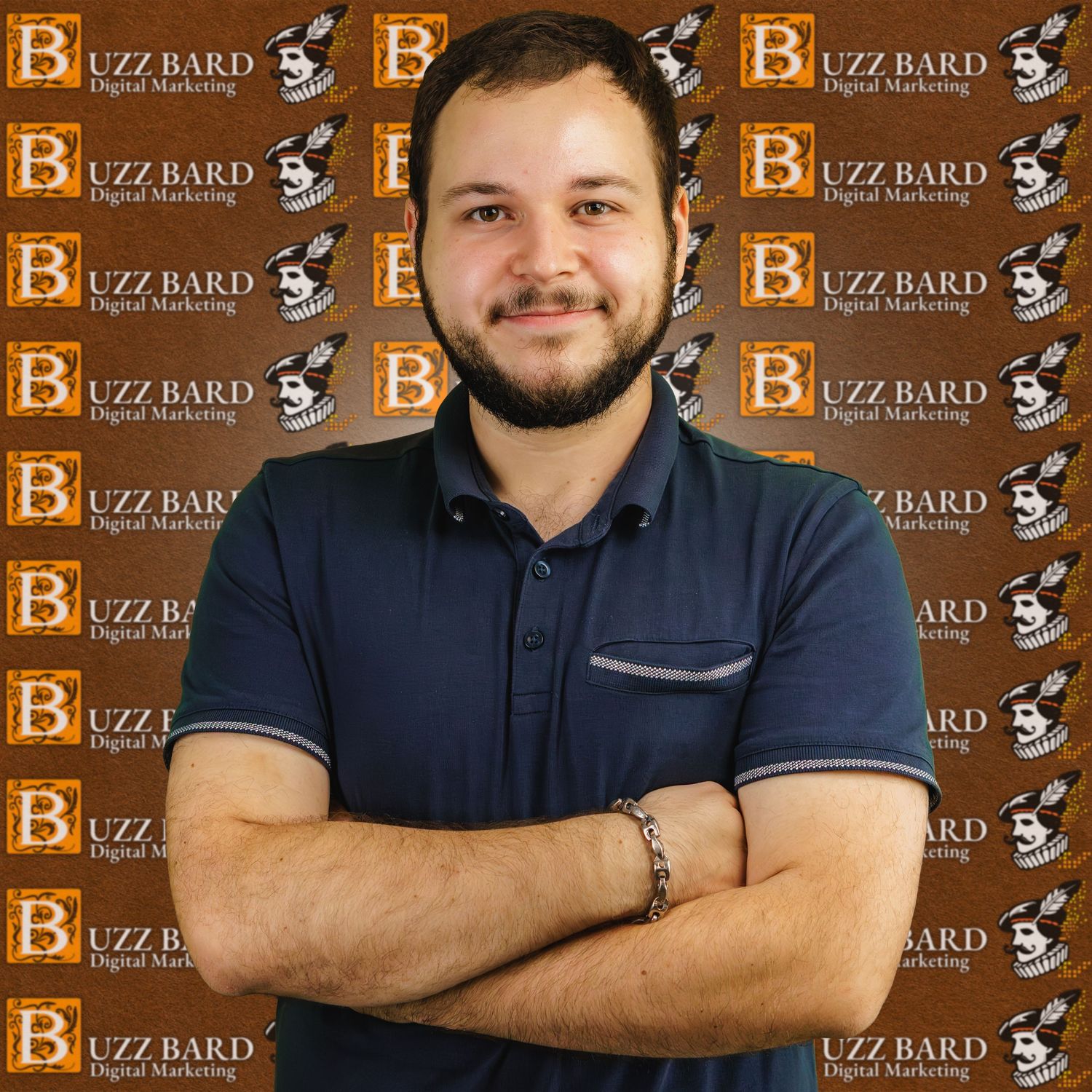 Professional headshot of someone in a navy polo shirt standing against a wall with repeating Buzz Bard logos.
