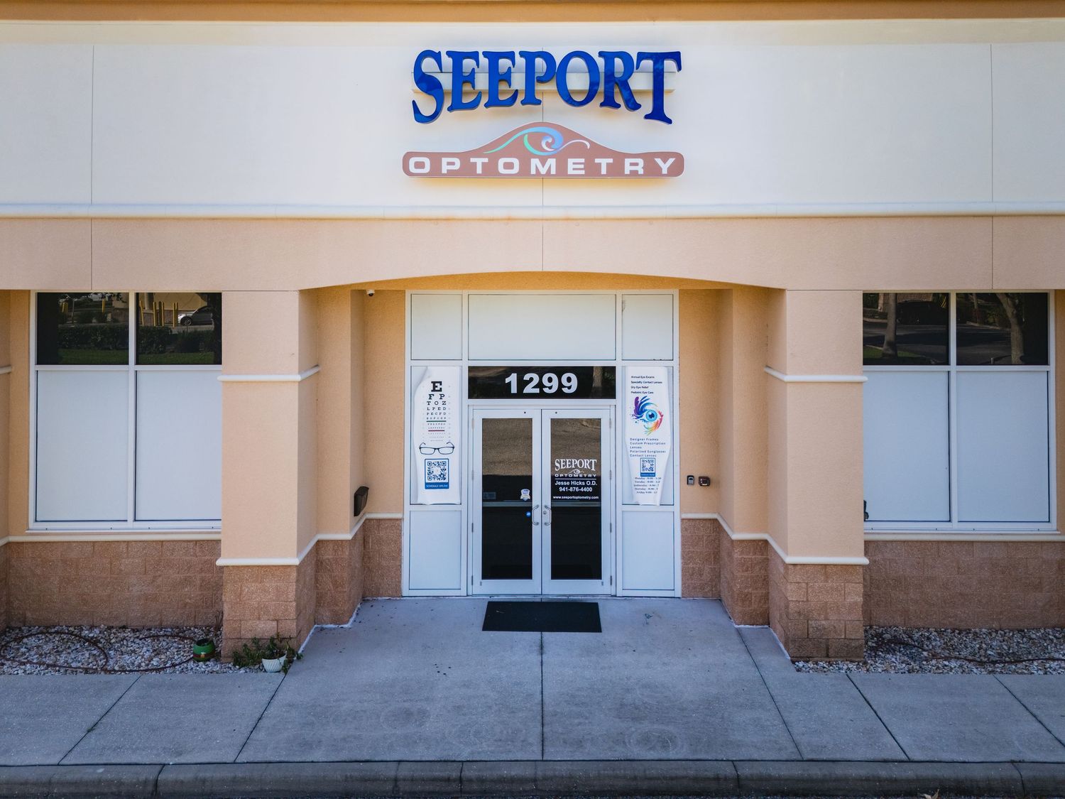 Exterior entrance of Seeport Optometry at suite 1299, featuring glass doors and a prominent blue sign.