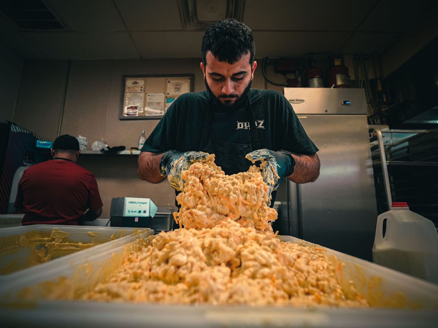 Chef preparing large batch of fresh dough on commercial kitchen countertop.
