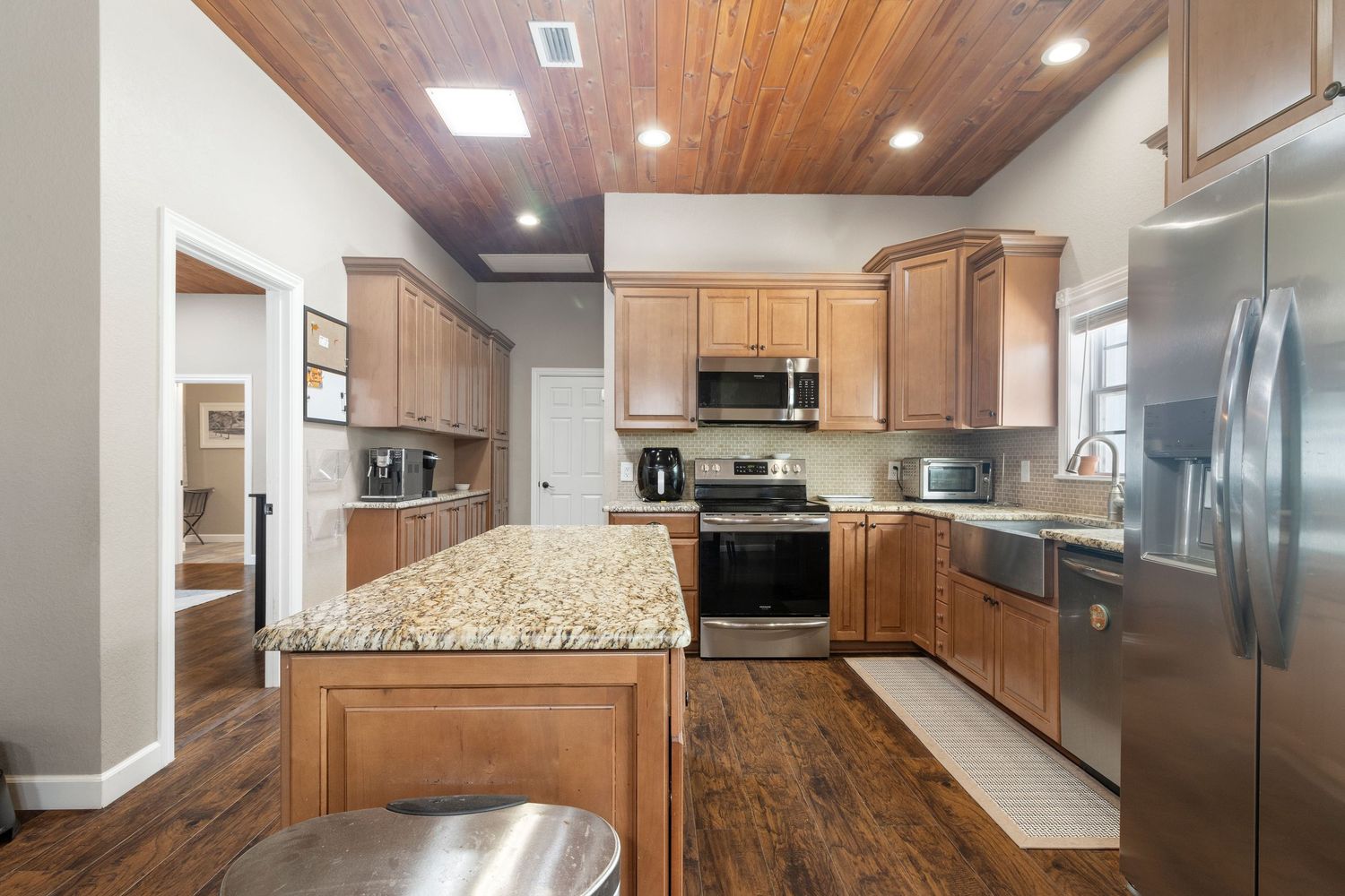 This modern kitchen features light wood cabinets, granite countertops, stainless steel appliances, and a hardwood floor.