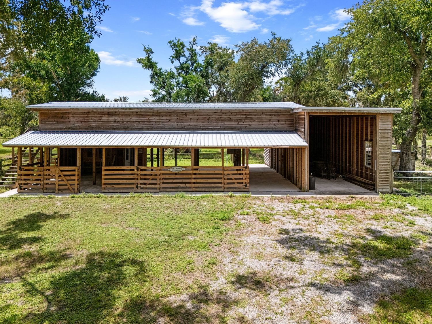 Long ranch-style building with covered walkway and wooden slat details surrounded by green trees and natural landscape.