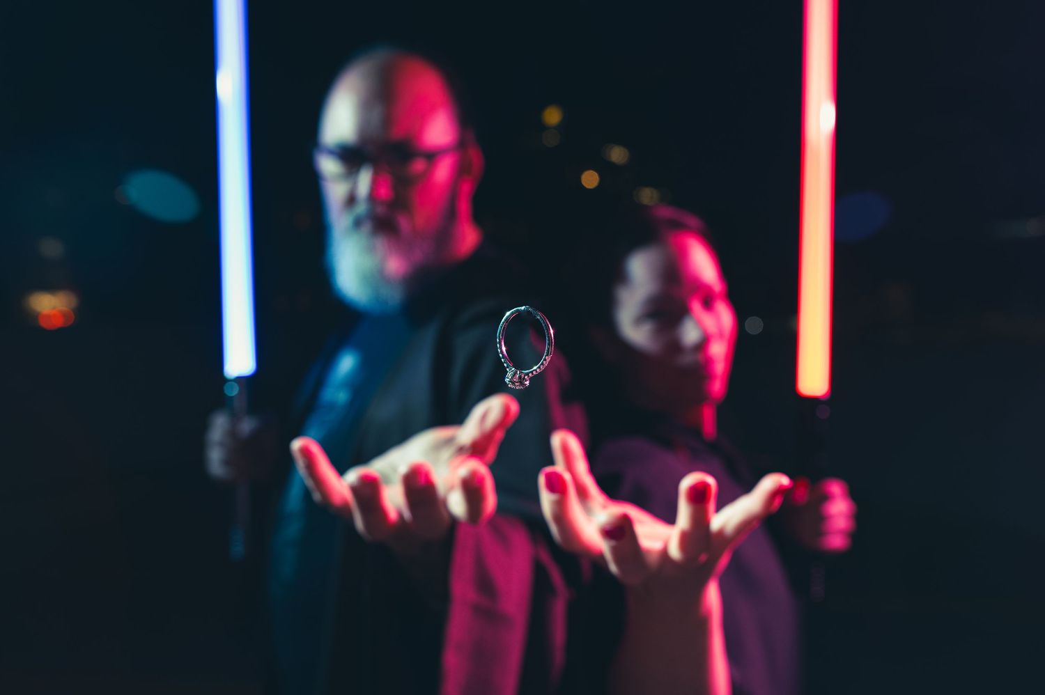 Glowing lightsabers illuminate a dark setting in blue and red hues. Knoxville Couple Photographer
