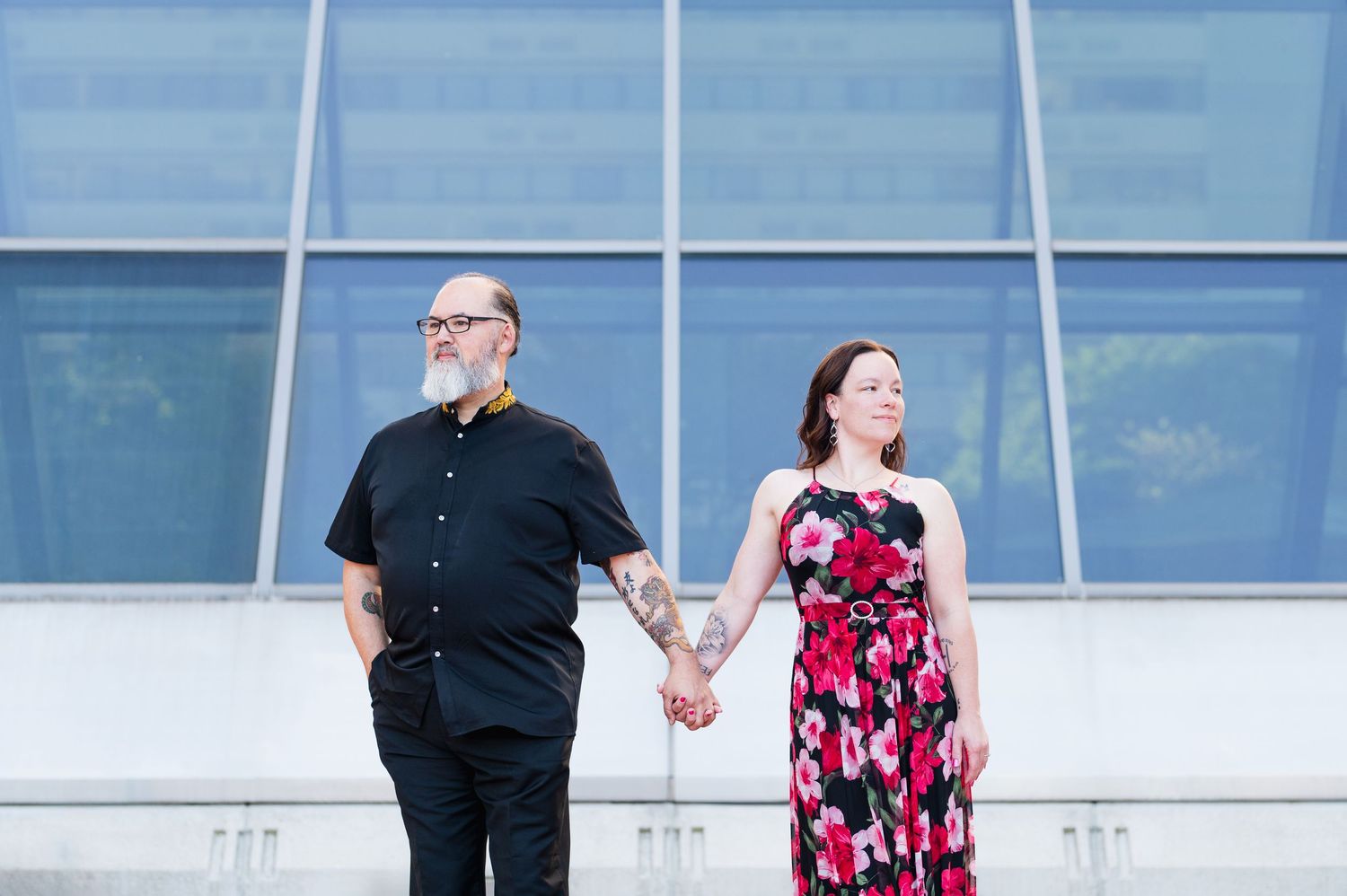 A couple shares a romantic moment in front of a modern glass building facade. Knoxville Couple Photographer. Market Square Knoxville