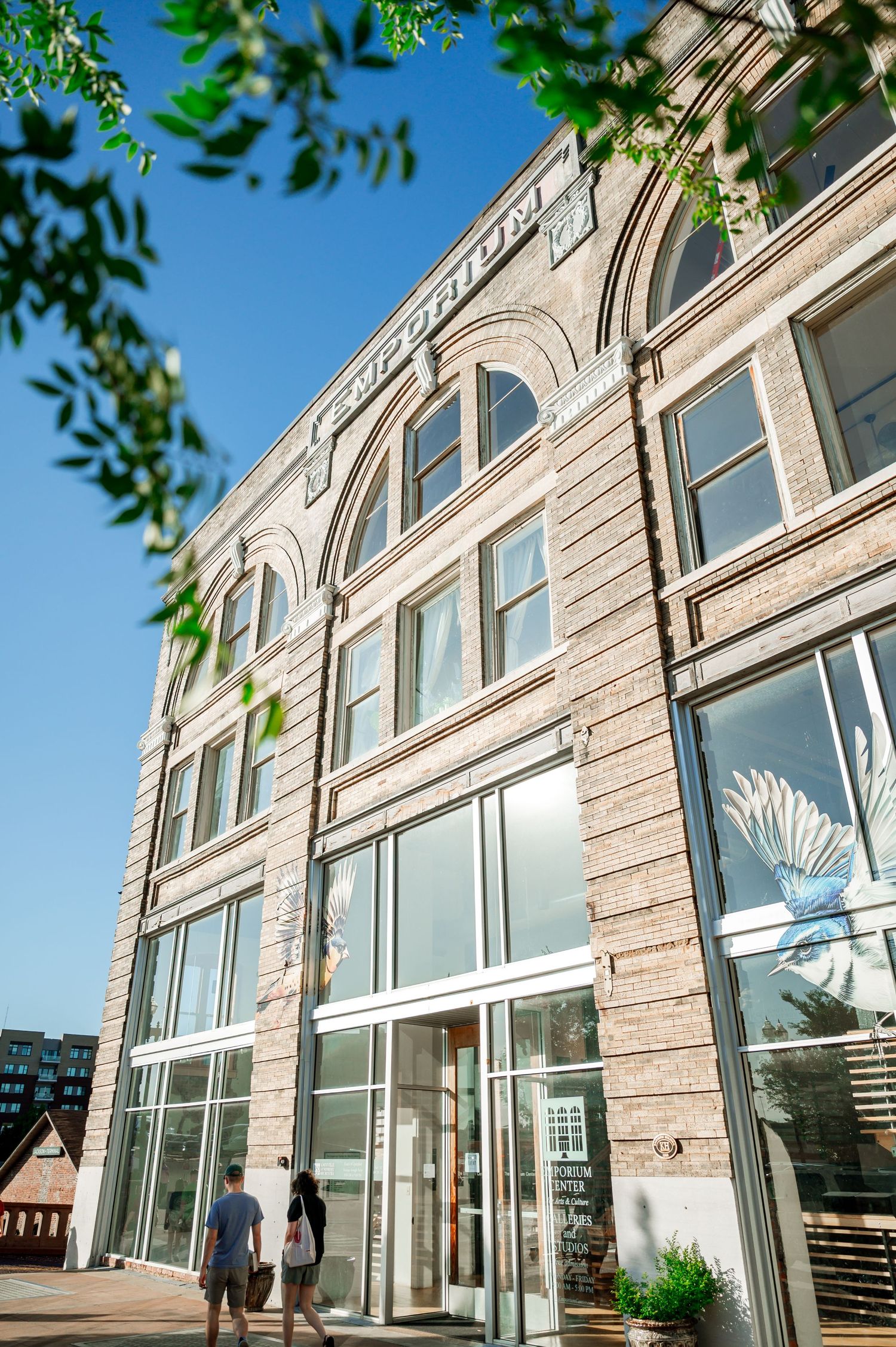 Modern stone building exterior with large glass windows and green foliage. Knoxville Wedding Photographer. Emporium Center