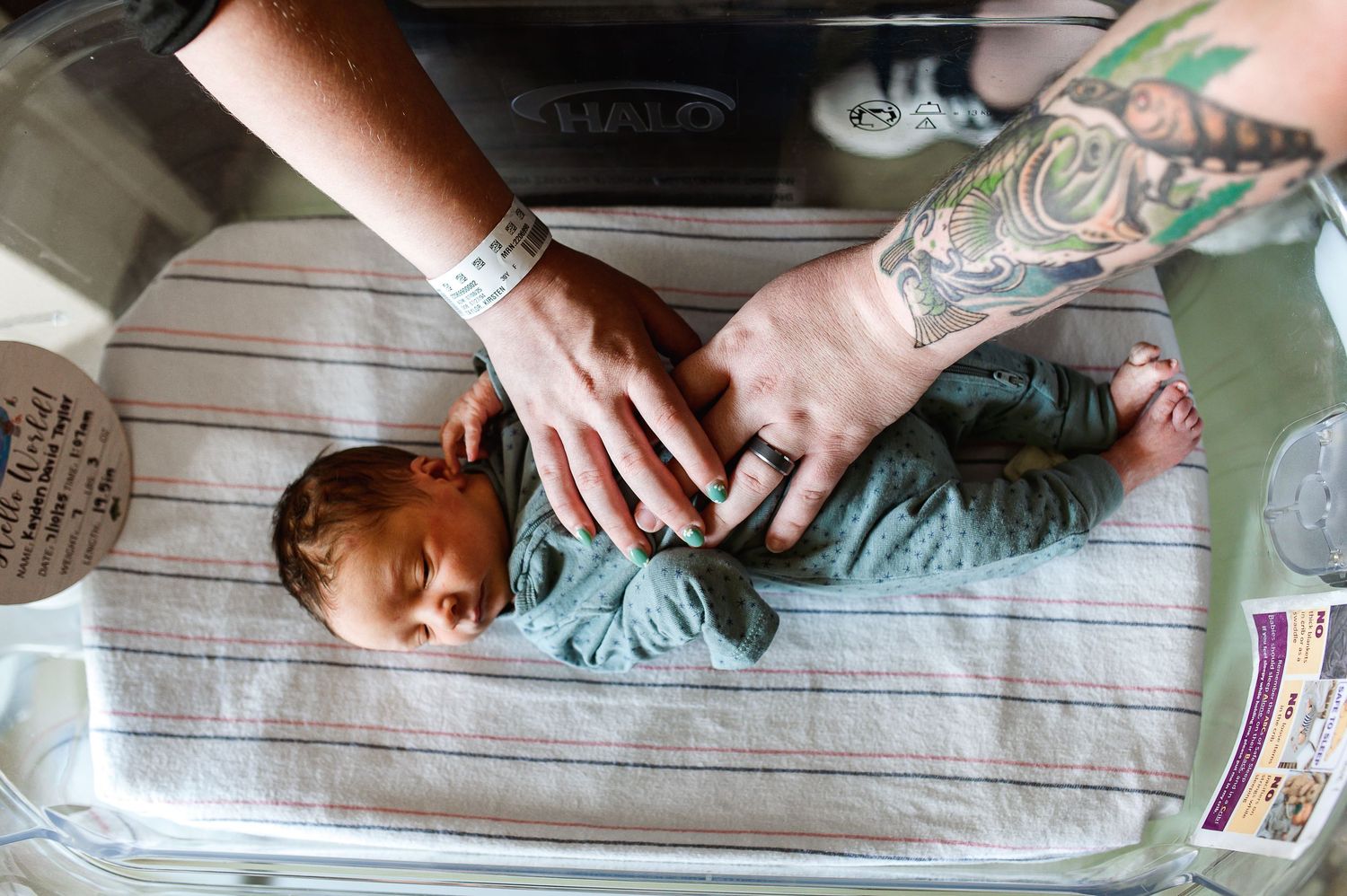 Hands reaching towards a baby on a changing table with striped fabric. Knoxville Newborn Photographer UT Medical Center