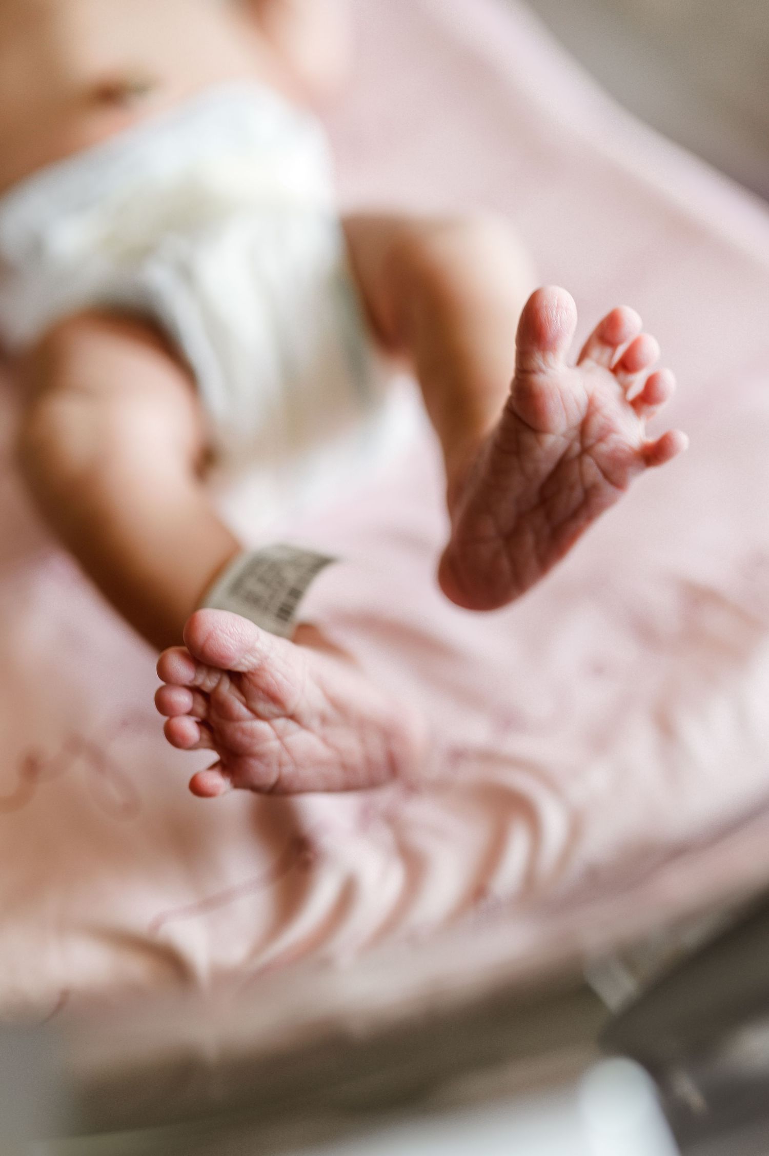 Tiny newborn feet resting on soft pink blanket in hospital. Knoxville Newborn Photographer