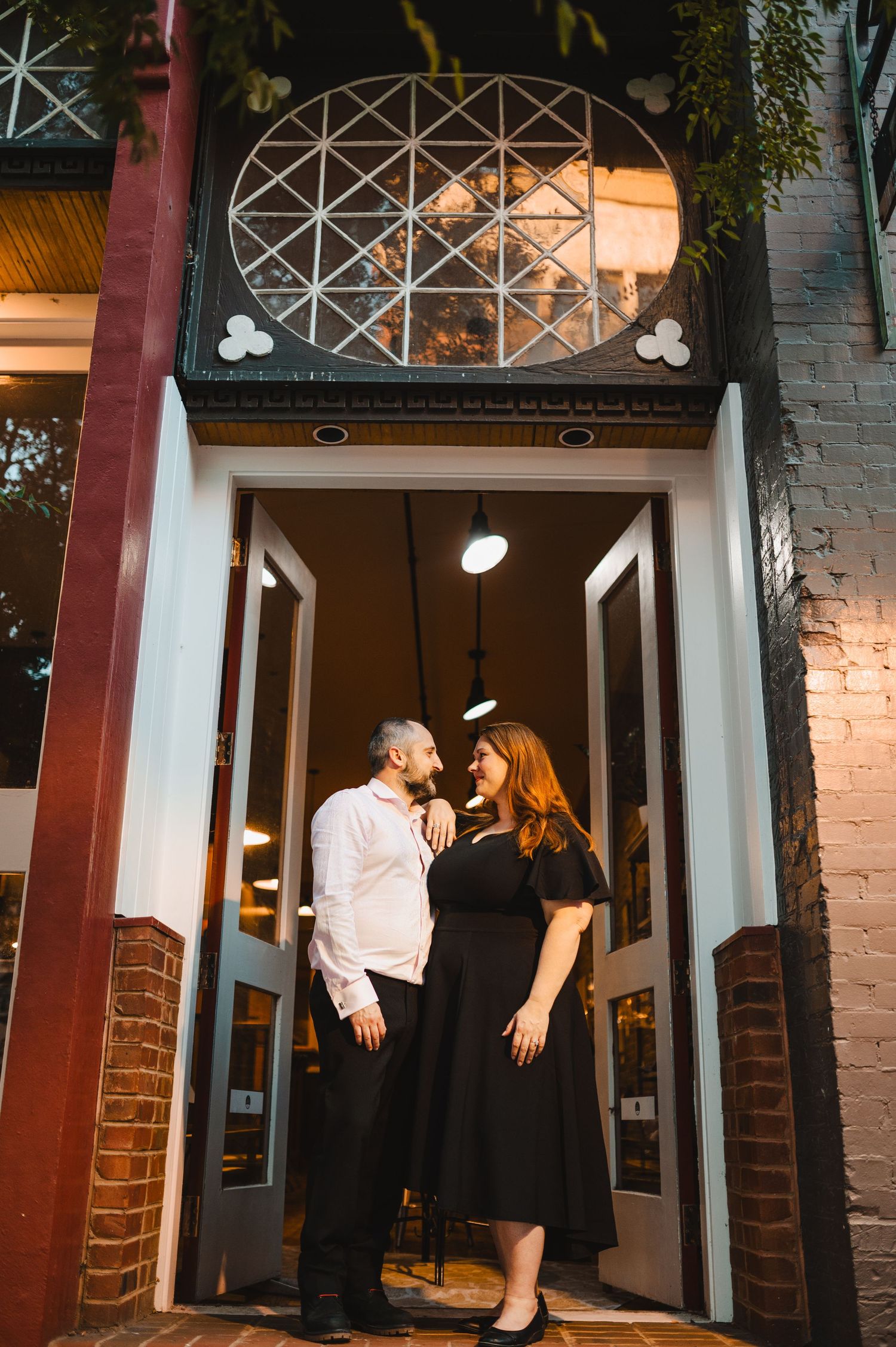 A couple sharing romantic moments outside a brick building with architectural details. Knoxville Couple Photographer