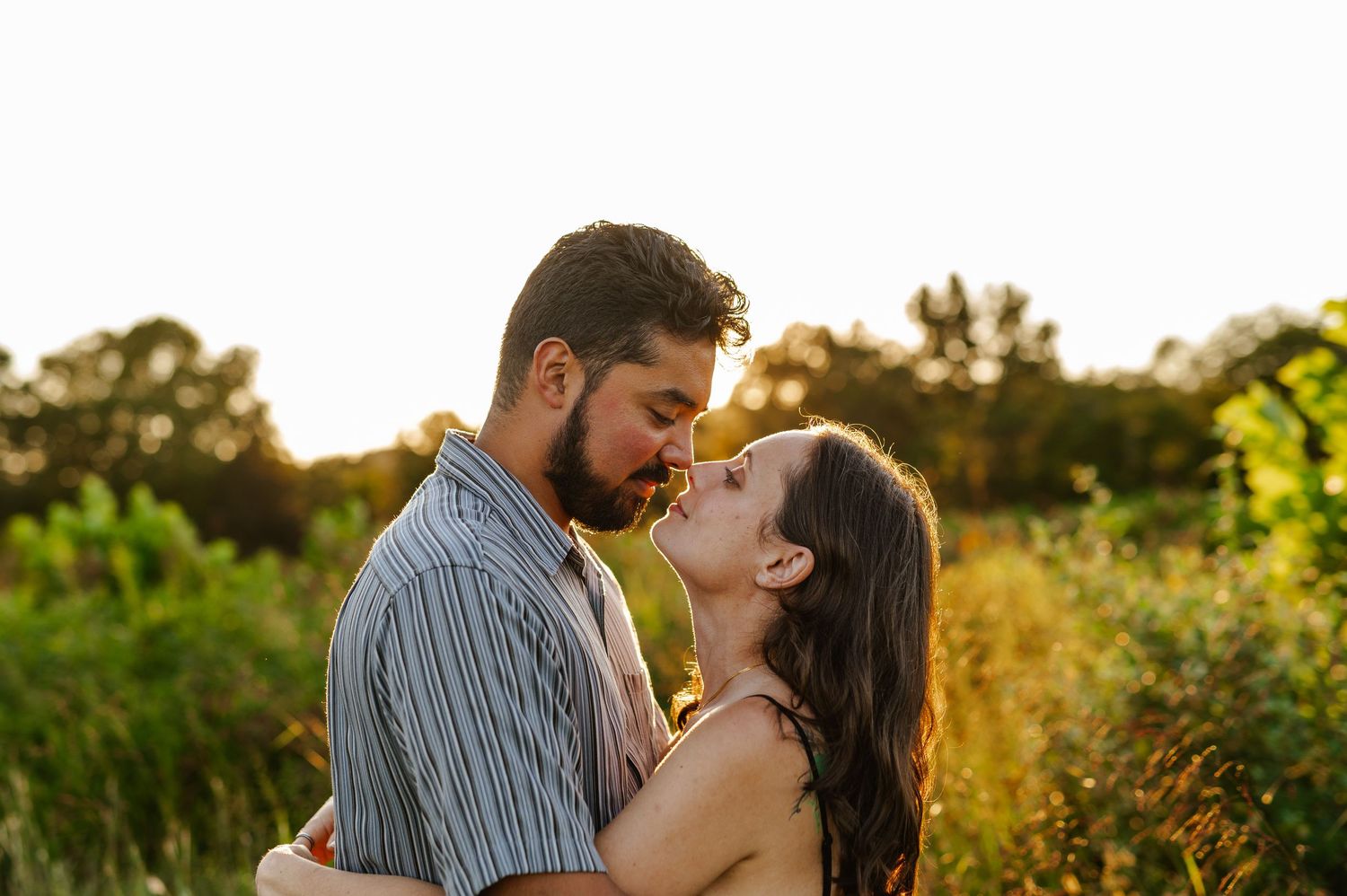 Intimate couple portrait against golden sunlit field during magic hour. Knoxville Couple Photographer. Melton Hills Park