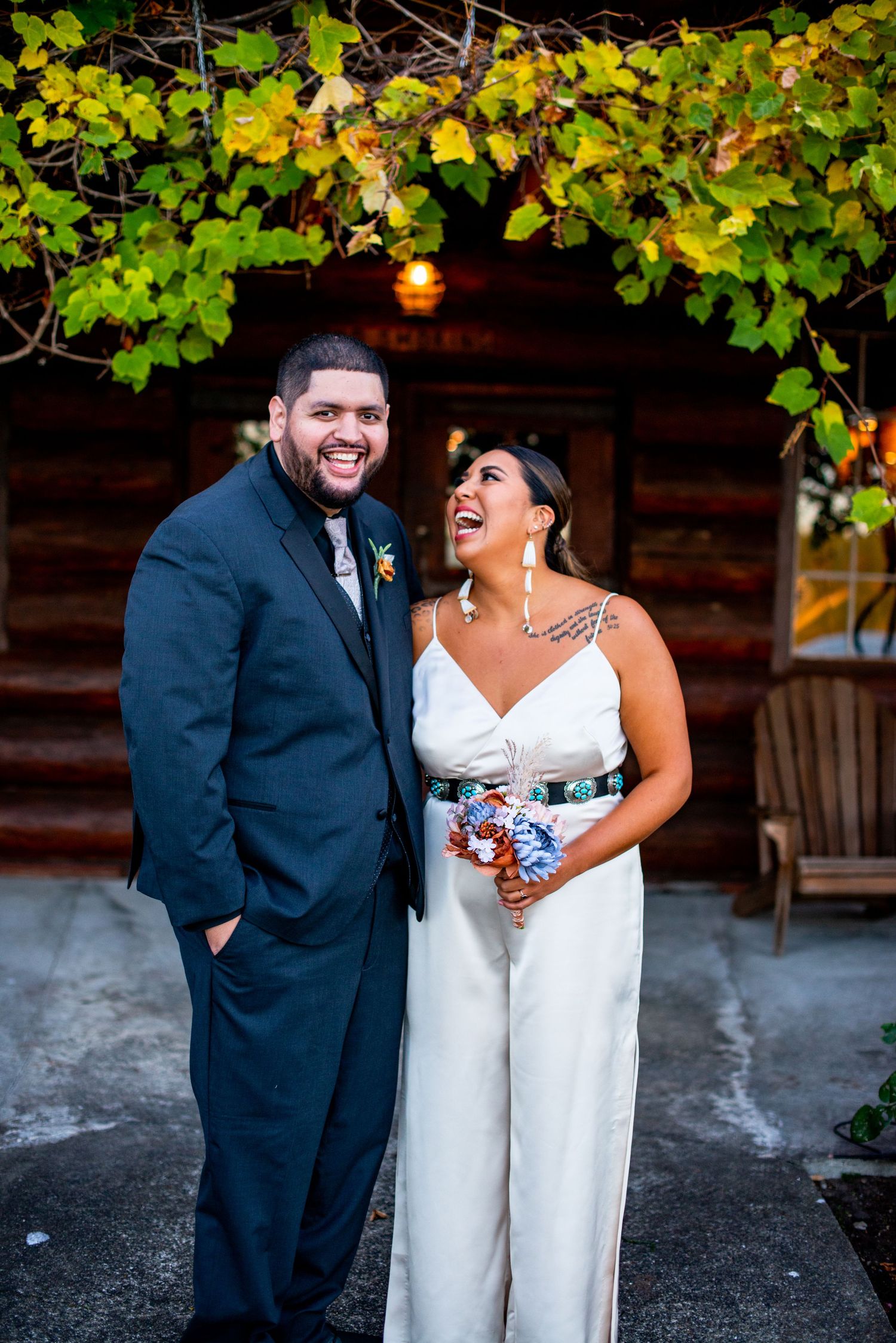 Couple shares joyful laughter under green foliage at outdoor venue. Knoxville Wedding Photographer