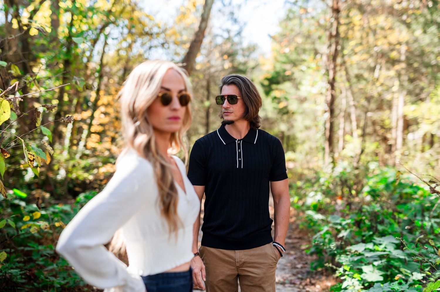 A fashionable couple explores a sunlit forest trail in coordinated casual outfits. Knoxville Couple Photographer.