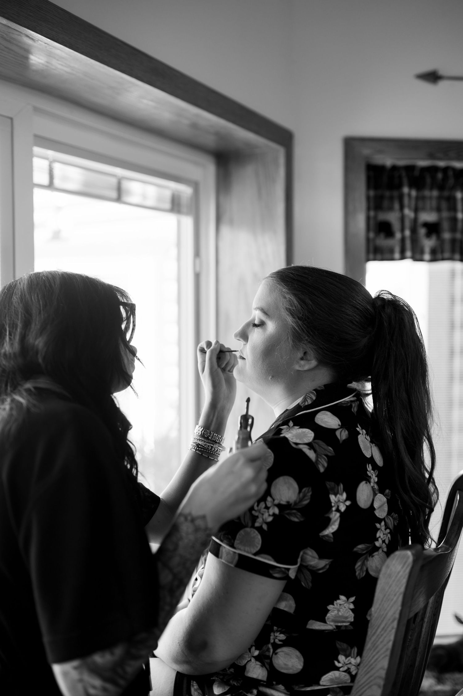 Wedding party members apply makeup in front of bright windows during preparation. Knoxville Wedding Photographer