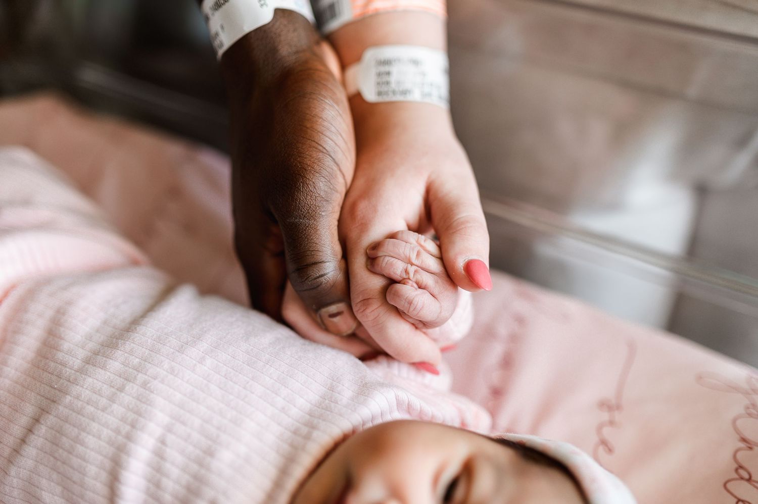 Gentle hands holding newborn baby's fingers against pink fabric. Knoxville Newborn Photographer