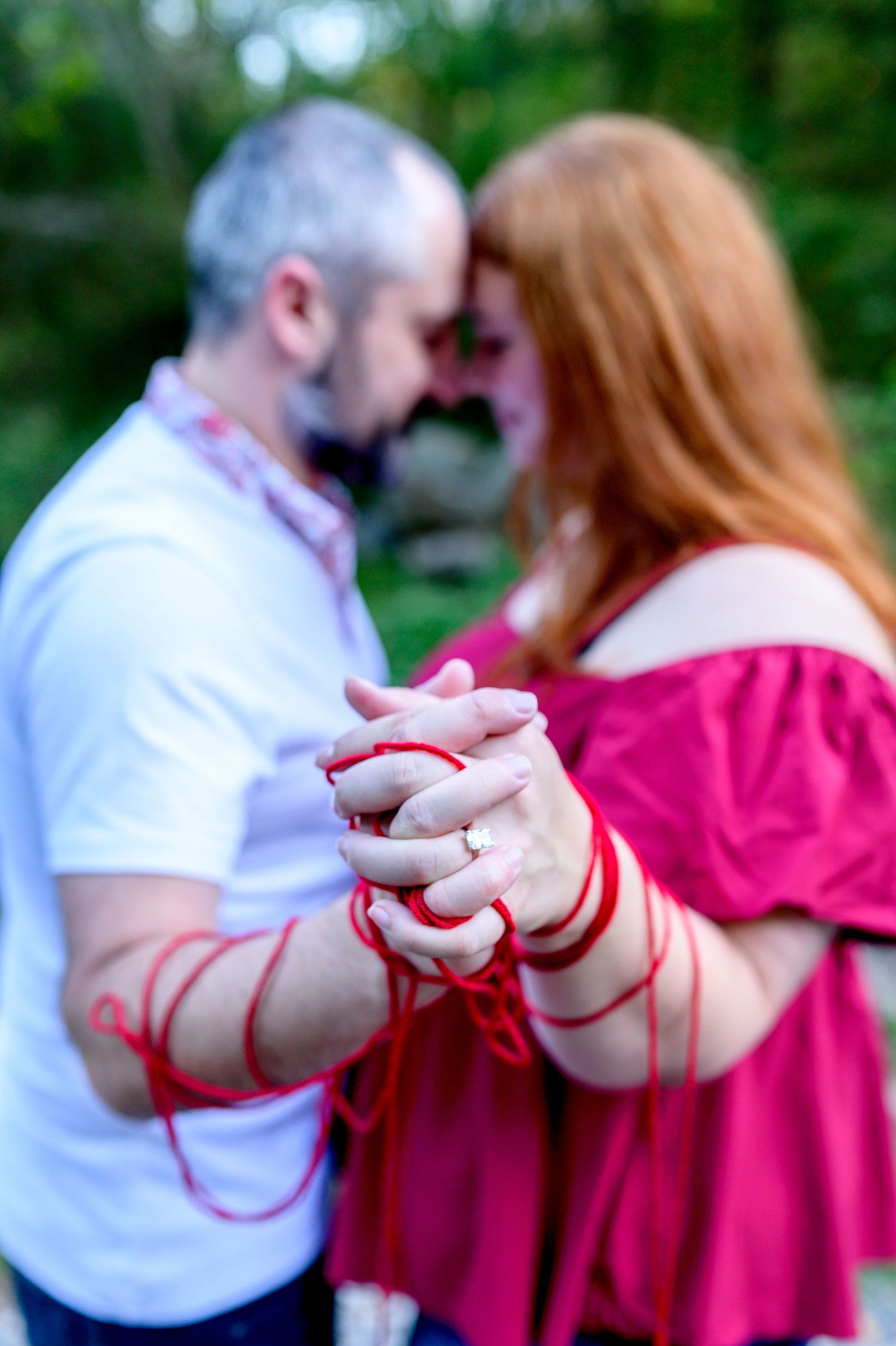 A couple holding hands with red string wrapped around them symbolizing their connection. Knoxville Couple Photographer