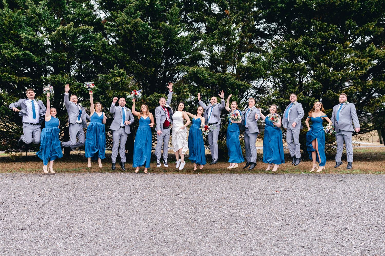 Wedding party in blue dresses and gray suits lines up for formal group photos outdoors. Knoxville Wedding Photographer