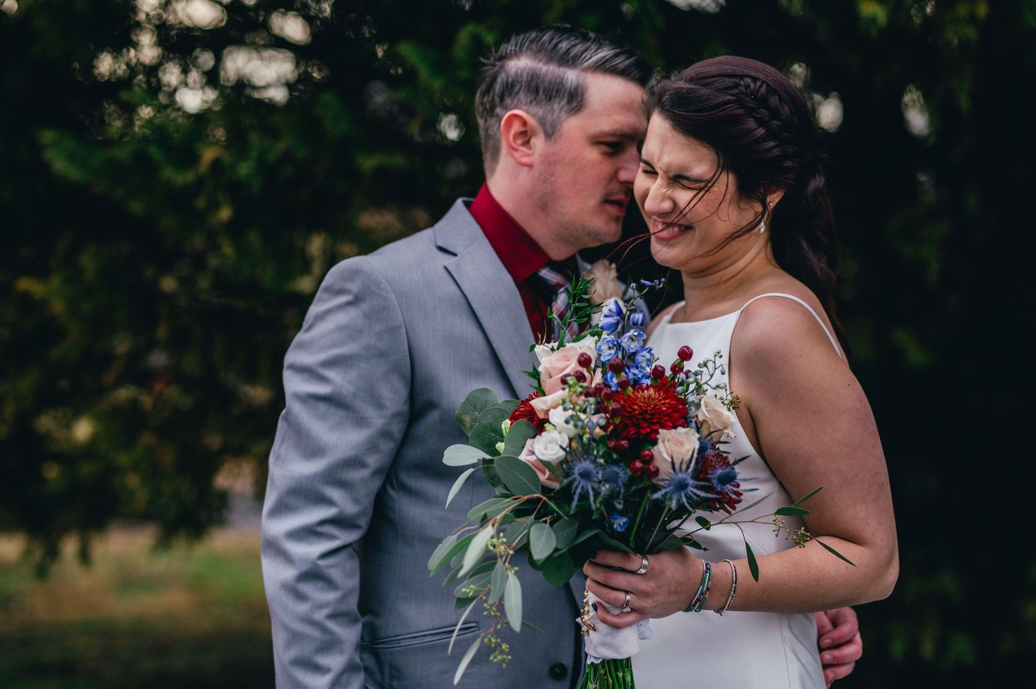 Newlyweds share tender moments while holding floral bouquet during outdoor wedding portraits. Knoxville Wedding Photographer