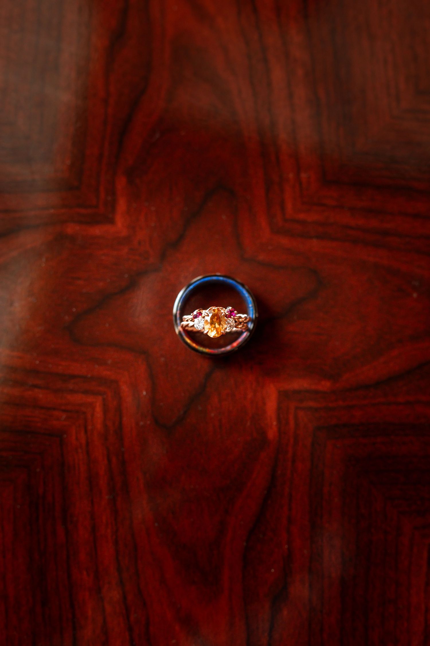 Wedding rings photographed on dark wooden surface with dramatic lighting. Knoxville Wedding Photographer