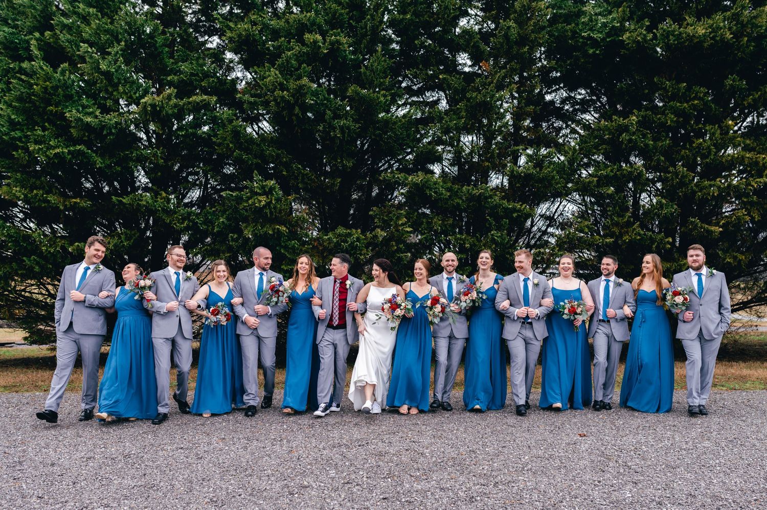 Wedding party members in blue and grey attire pose together outdoors. Knoxville Wedding Photographer