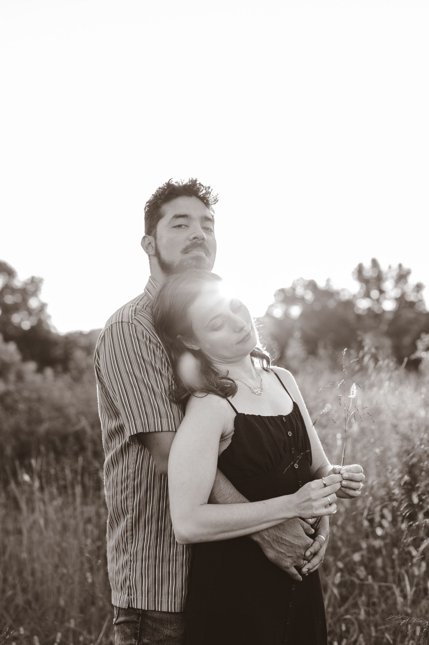 Romantic black and white portrait of a couple embracing in a field at sunset. Knoxville Couple Photographer