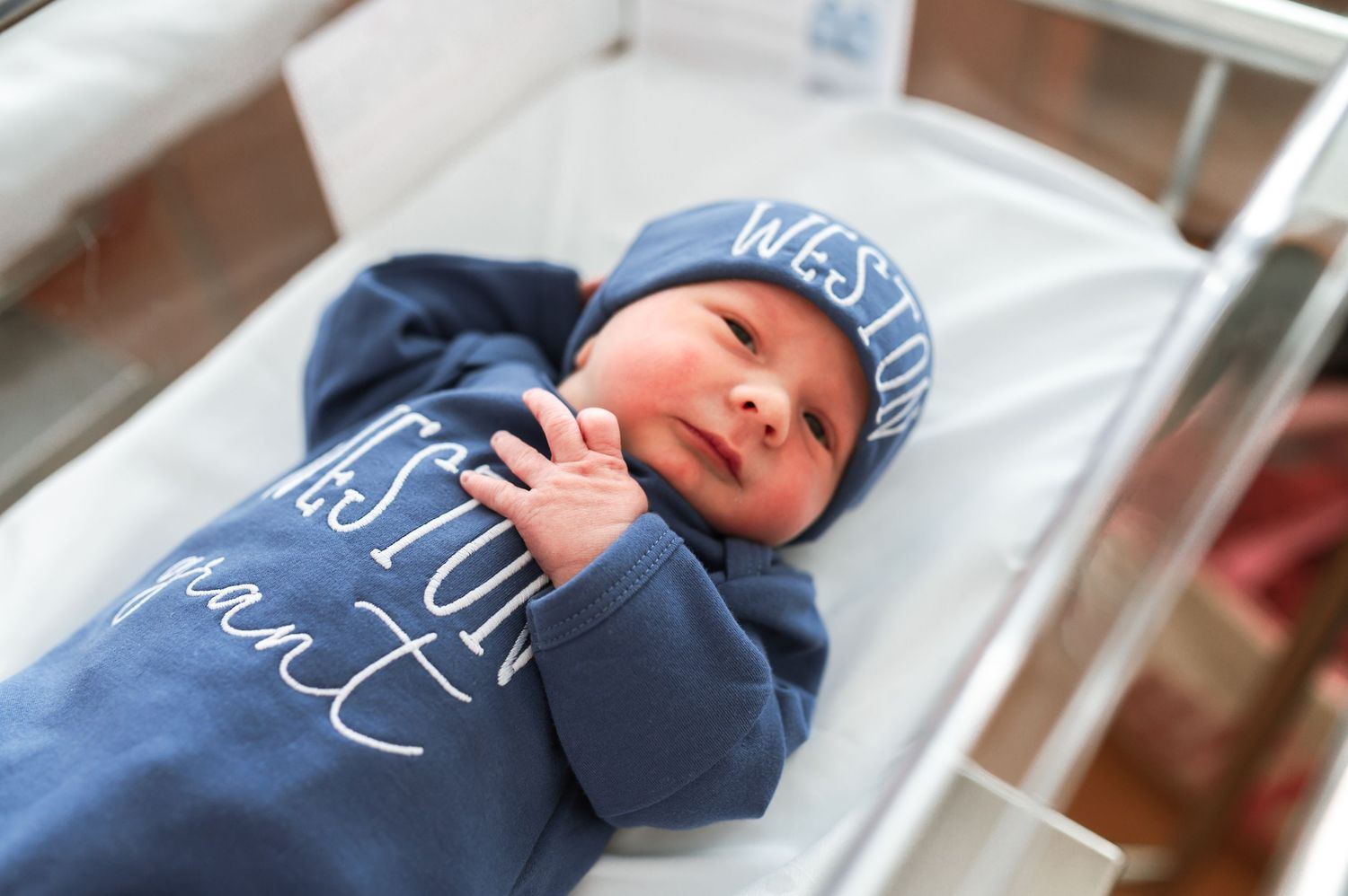 Newborn wearing blue hat resting in hospital bassinet. Knoxville Newborn Photographer UT Medical Center
