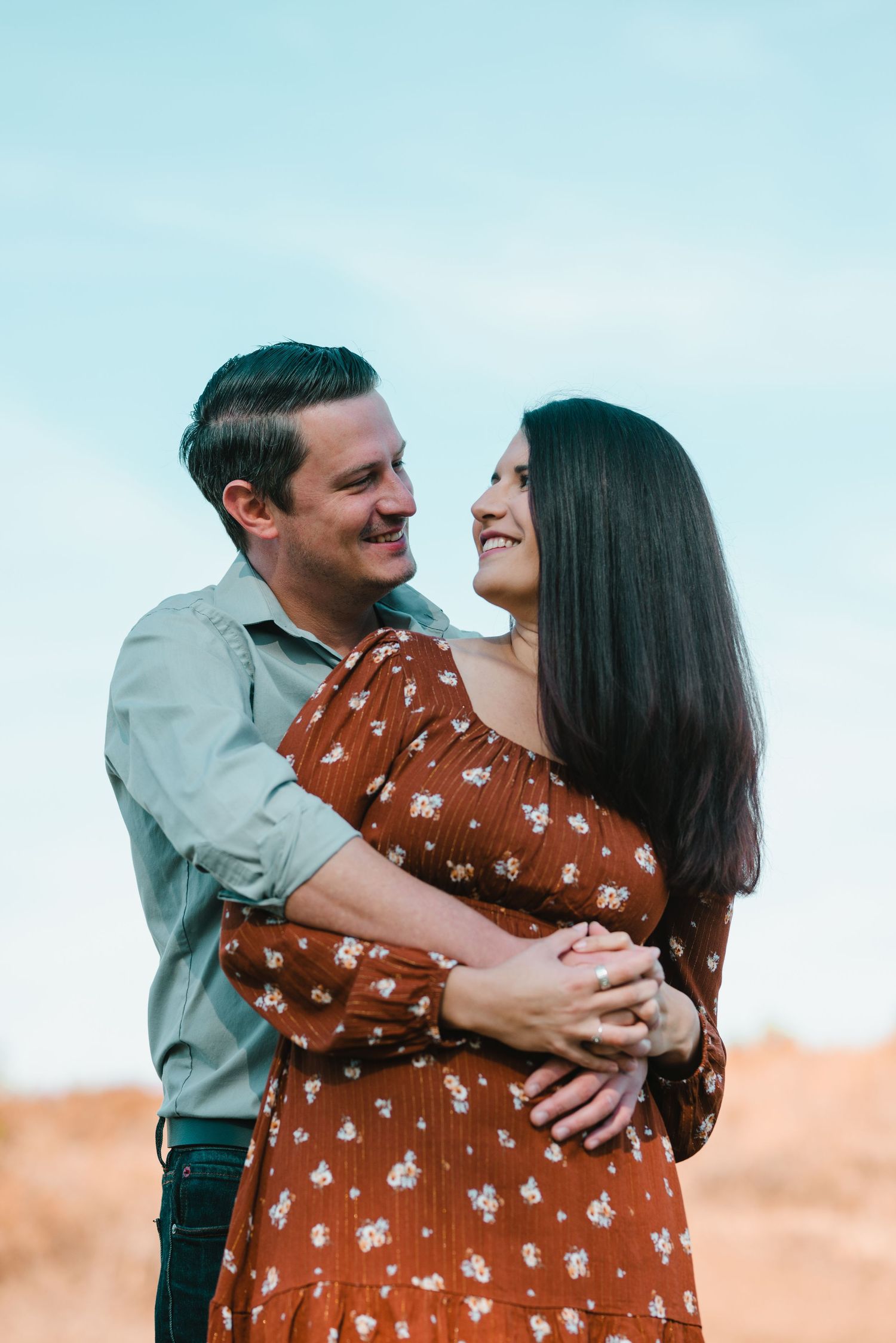 A couple shares an intimate moment while embracing against a bright blue sky. Knoxville Couple Photographer