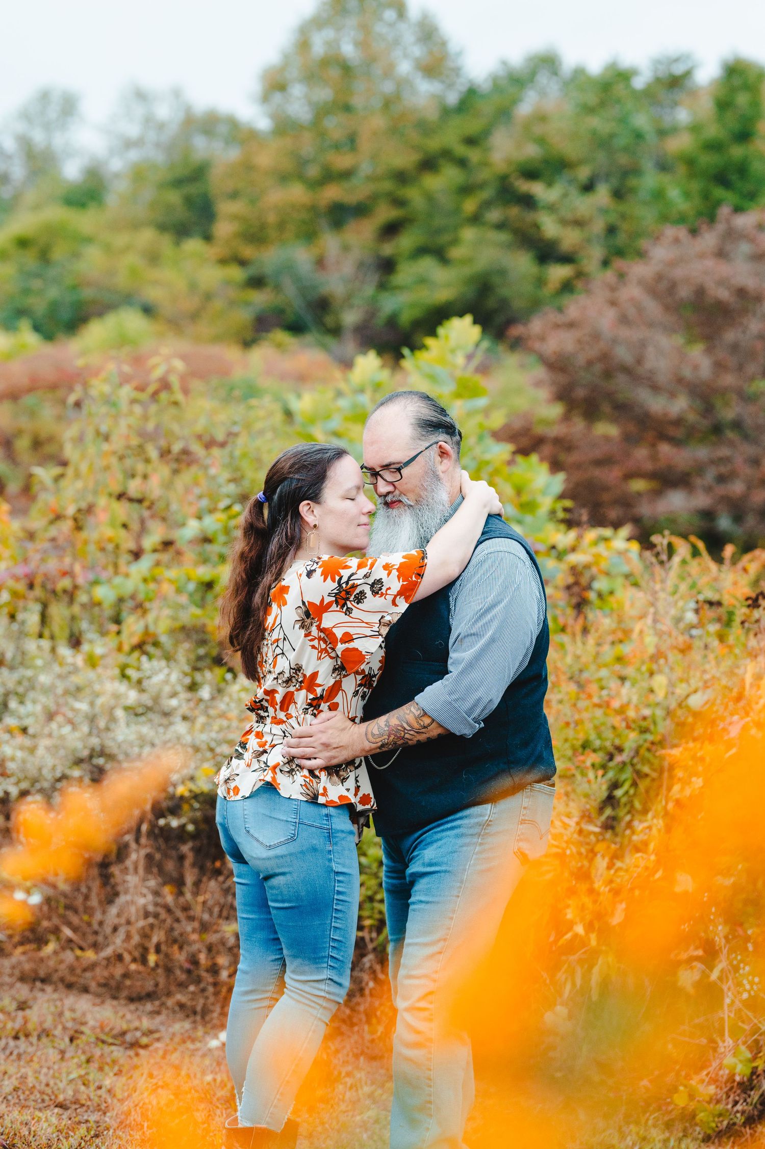 A romantic autumn photoshoot with orange wildflowers in the foreground. Knoxville Couple Photographer