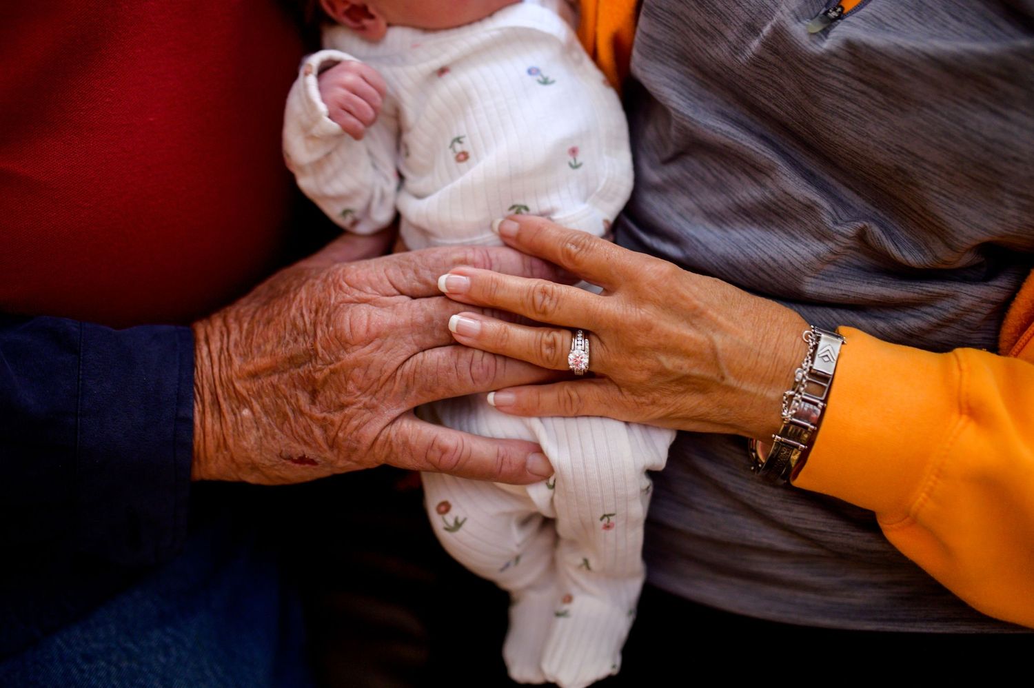 Elderly hands with jewelry holding a small baby wrapped in white. Knoxville Newborn Photographer UT Medical Center