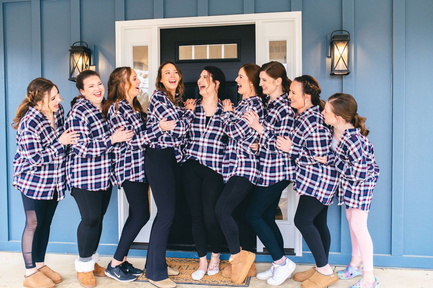A group wearing matching plaid flannel shirts poses playfully in front of a blue door. Knoxville Wedding Photographer