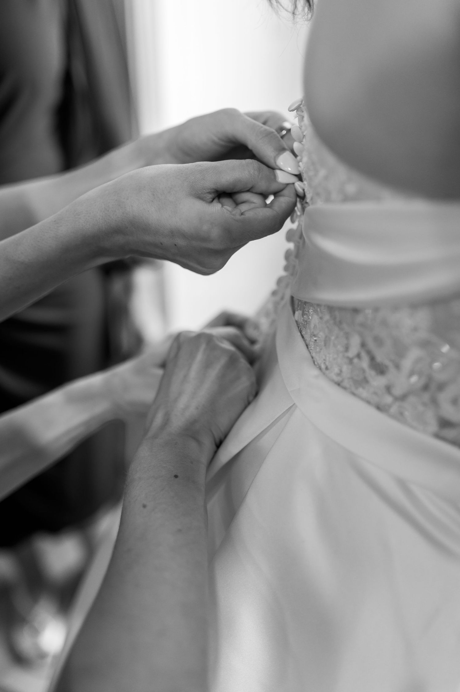 Detailed shots of hands fastening and adjusting a white wedding dress. Knoxville Wedding Photographer