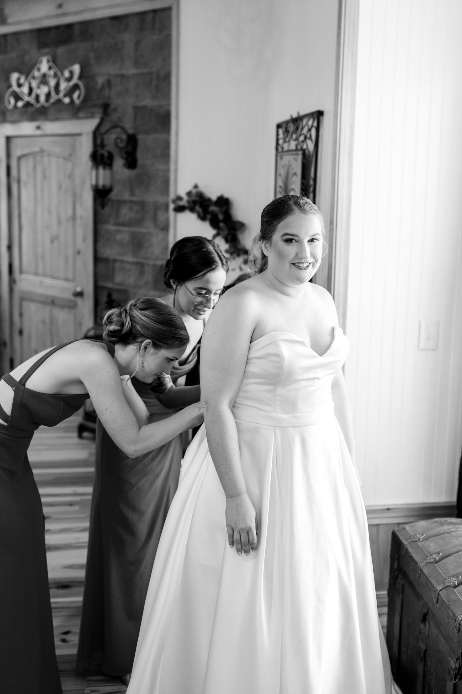 Black and white images of wedding dress preparations with attendants helping the bride. Knoxville Wedding Photographer