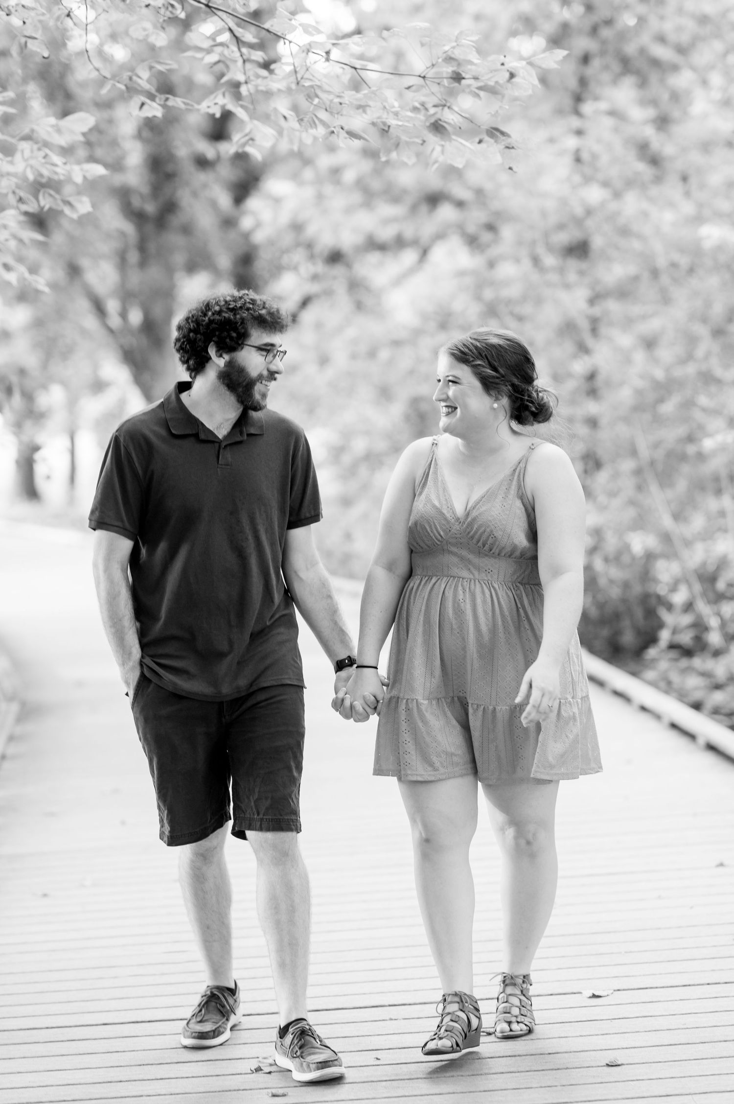 Black and white engagement photos of couple walking hand in hand on wooden boardwalk. Knoxville Couple Photographer