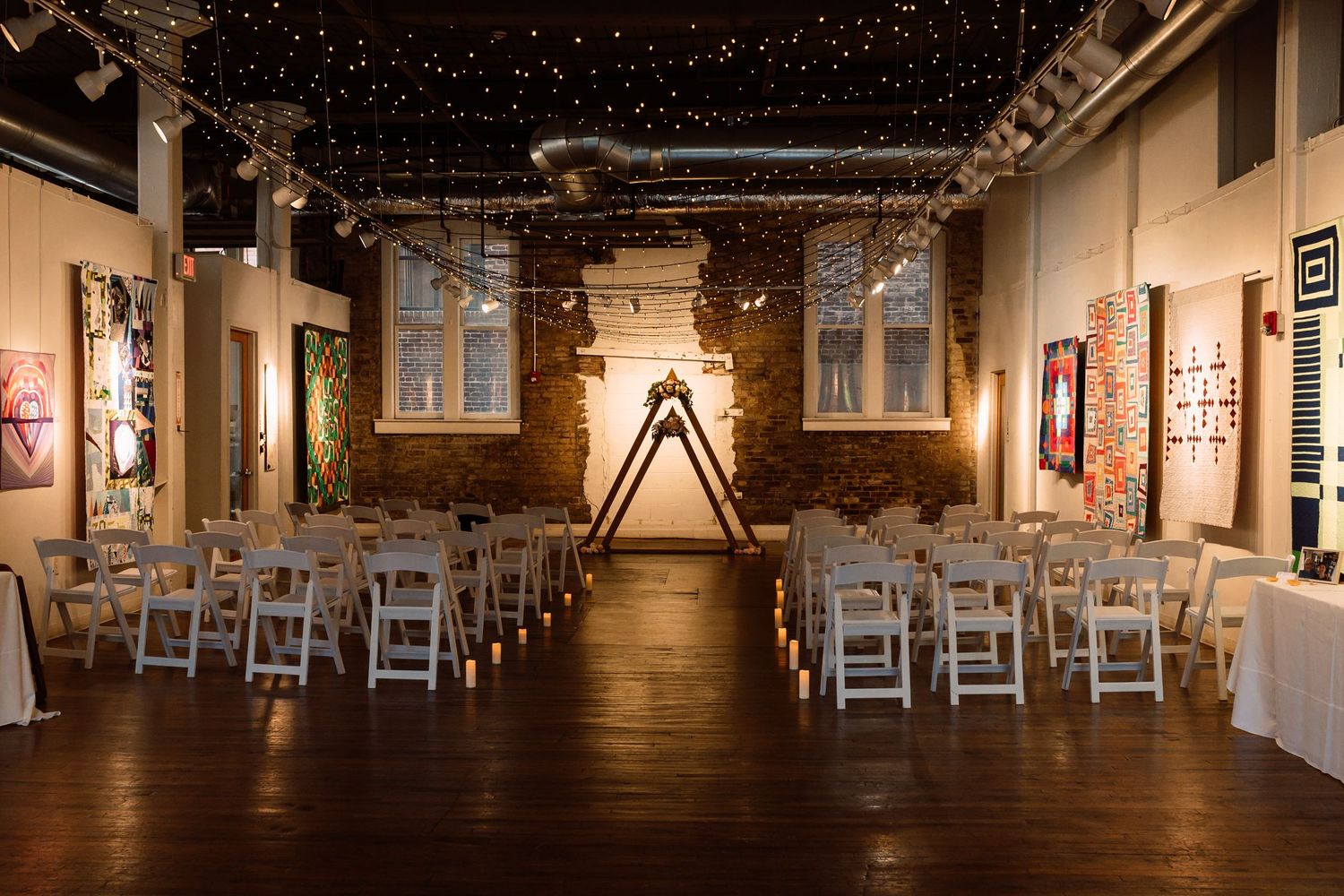 Panoramic view of an elegant wedding reception venue with white chairs and string lights overhead. Knoxville Wedding Photographer. Emporium