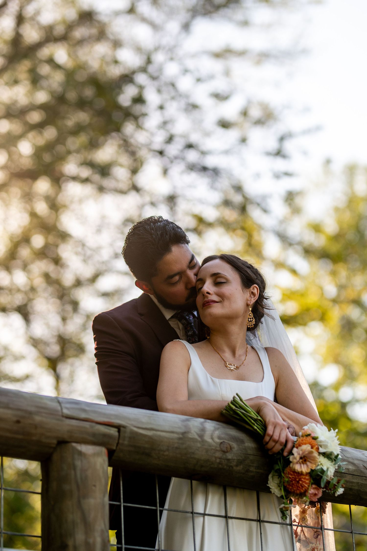 Romantic couple sharing tender moments by a wooden fence during golden hour. Knoxville Wedding Photographer