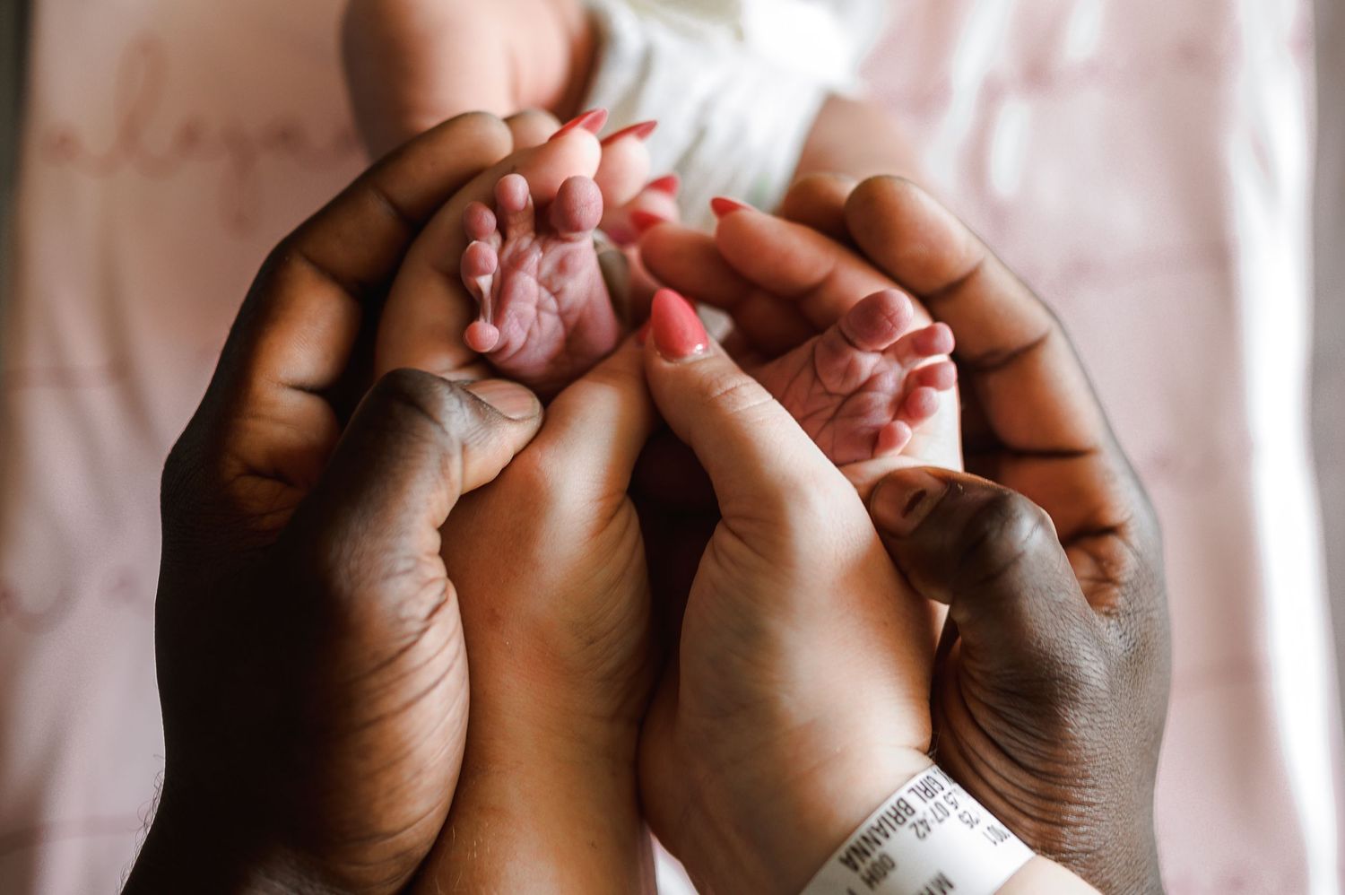 Adult hands tenderly holding newborn baby's tiny fingers. Knoxville Newborn Photographer UT Medical Center