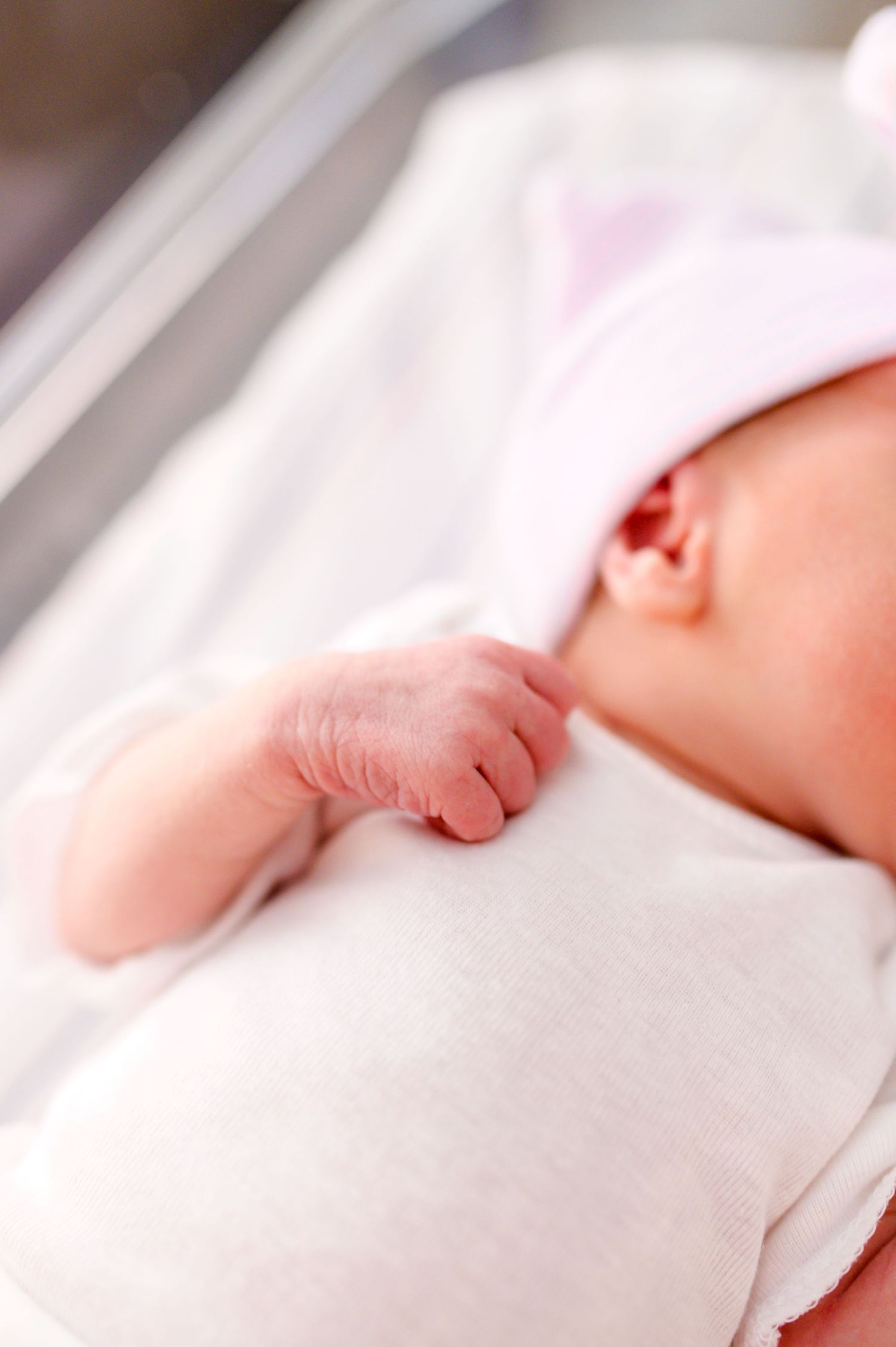 Close-up view of a sleeping newborn's tiny hand and arm against white blankets. Knoxville Newborn Photographer