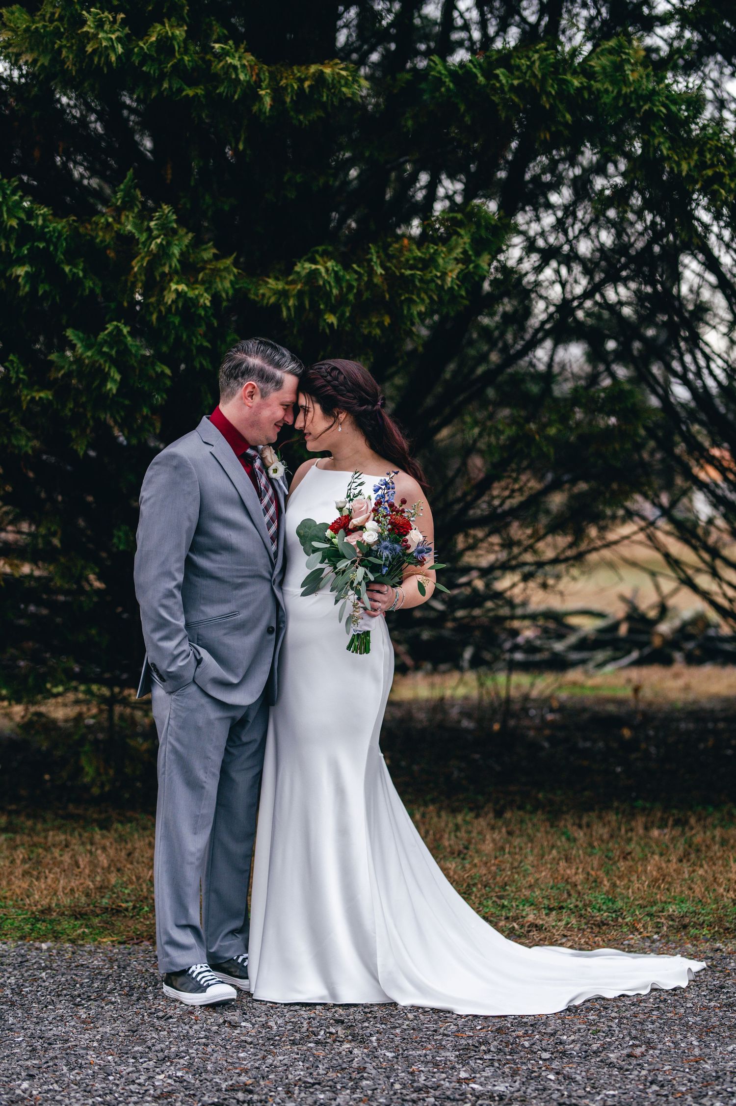 A romantic wedding couple shares an intimate moment on a gravel path surrounded by autumn trees. Knoxville Wedding Photographer