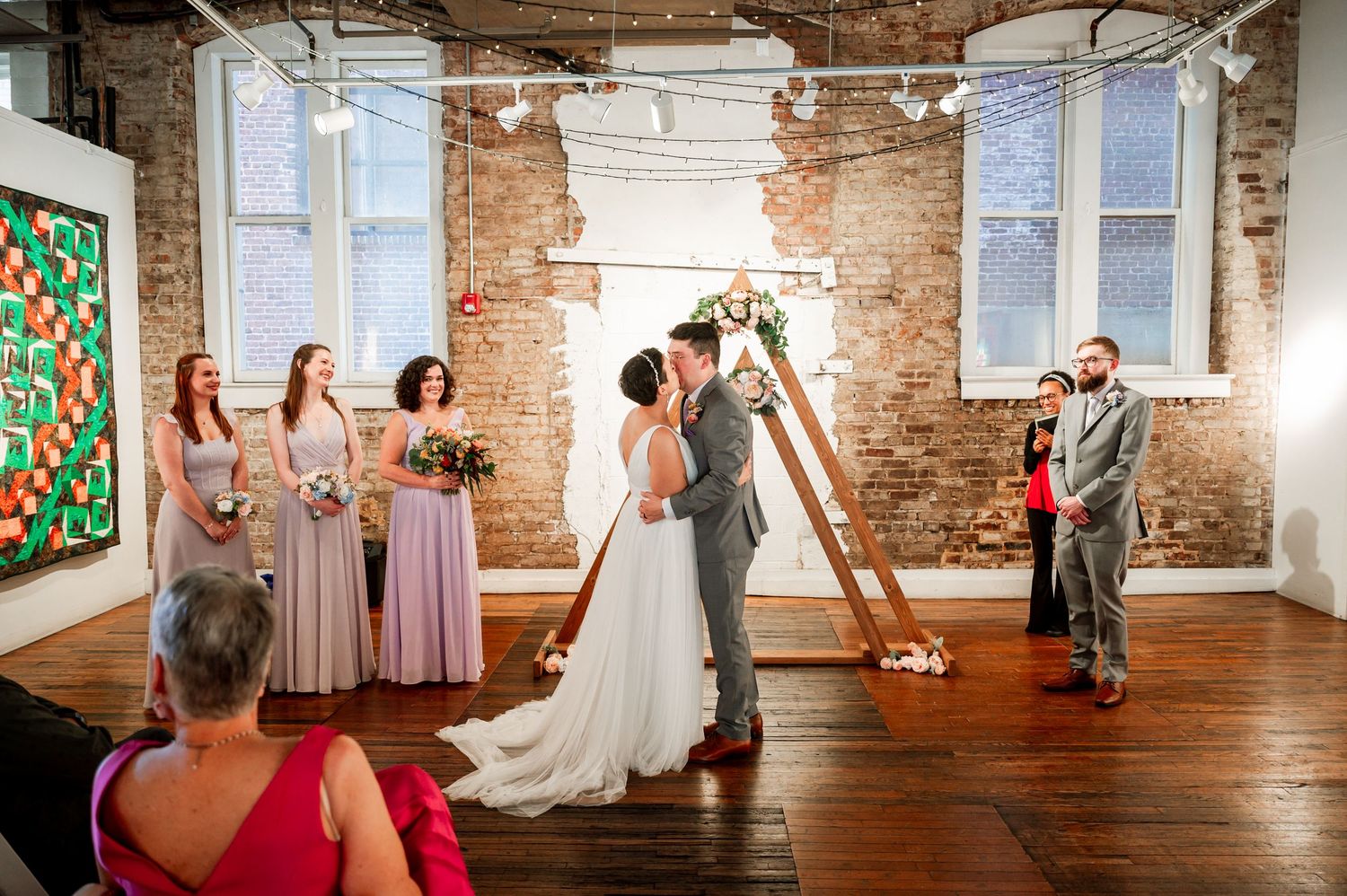 Wedding celebration in a rustic brick-walled venue with string lights and hardwood floors. Knoxville Wedding Photographer