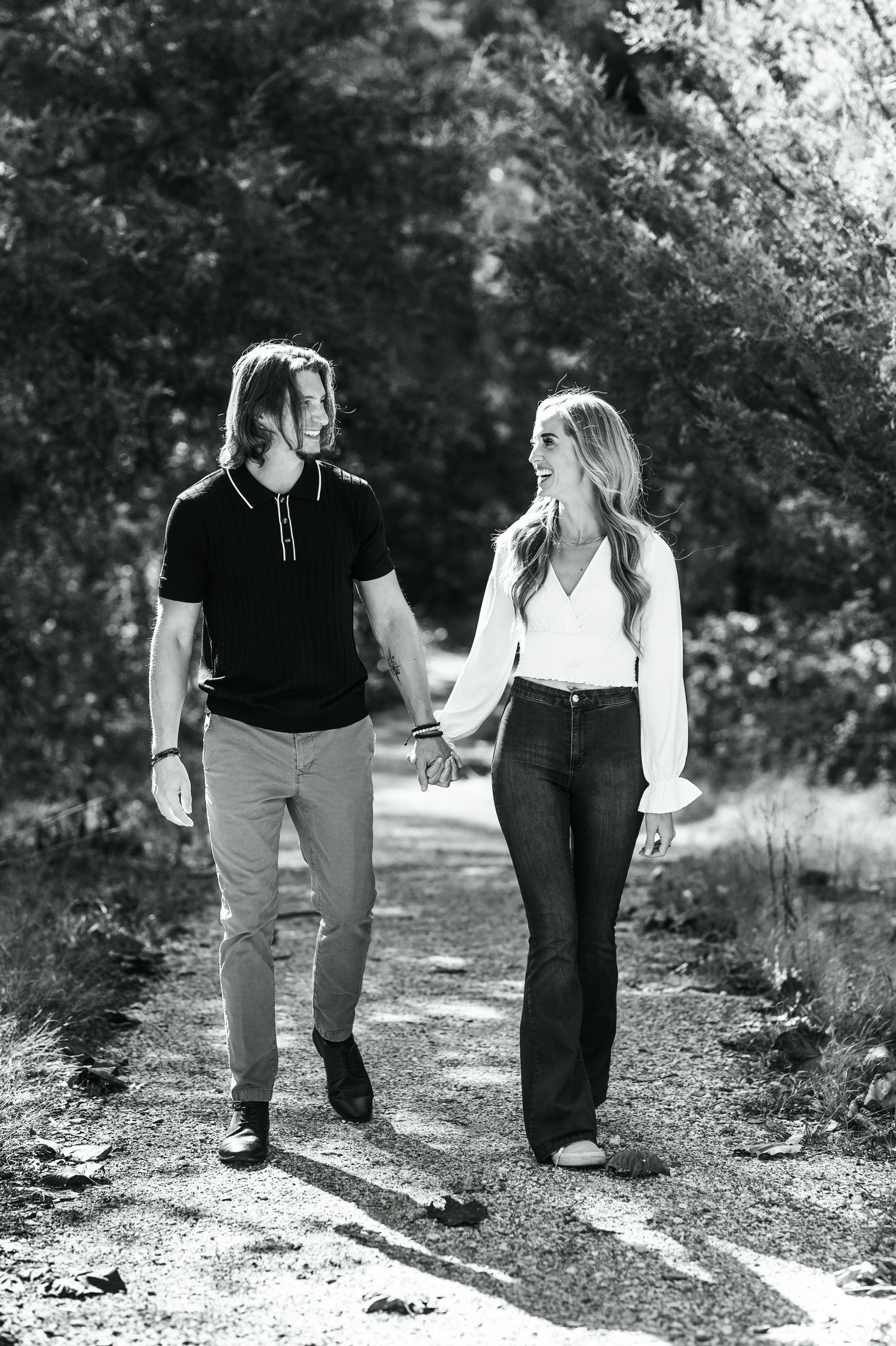 A couple walks together on a forest path in black and white photography. Knoxville Couple Photographer