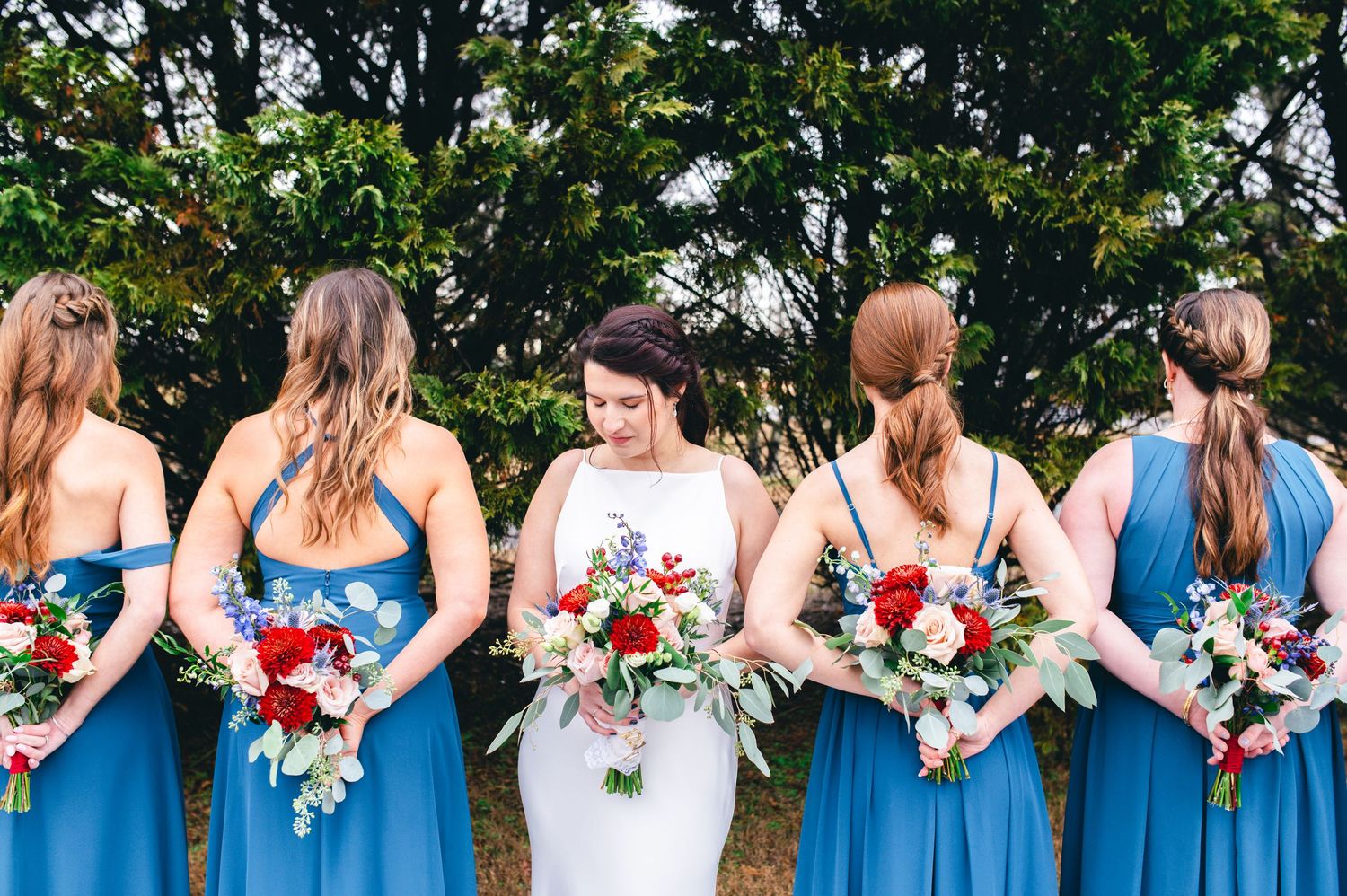 Bridesmaids in blue dresses hold colorful bouquets while standing in a row. Knoxville Wedding Photographer